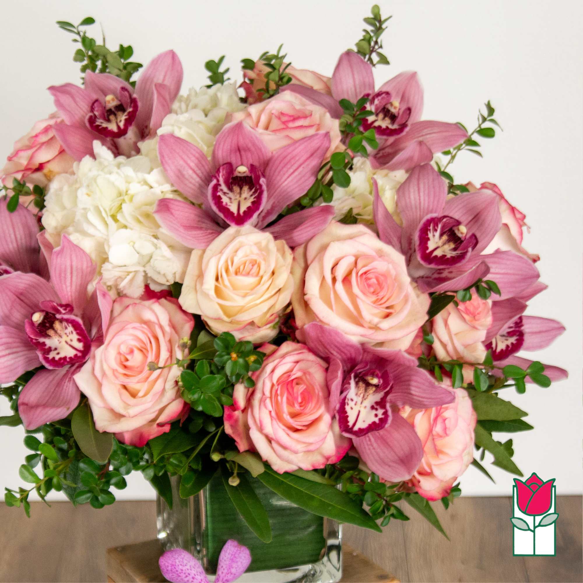 Pink roses and orchids arranged in a clear glass vase