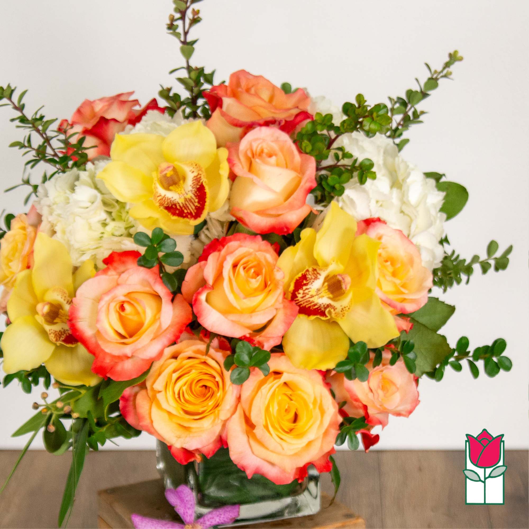 Bouquet of peach and yellow roses with orchids in a glass vase