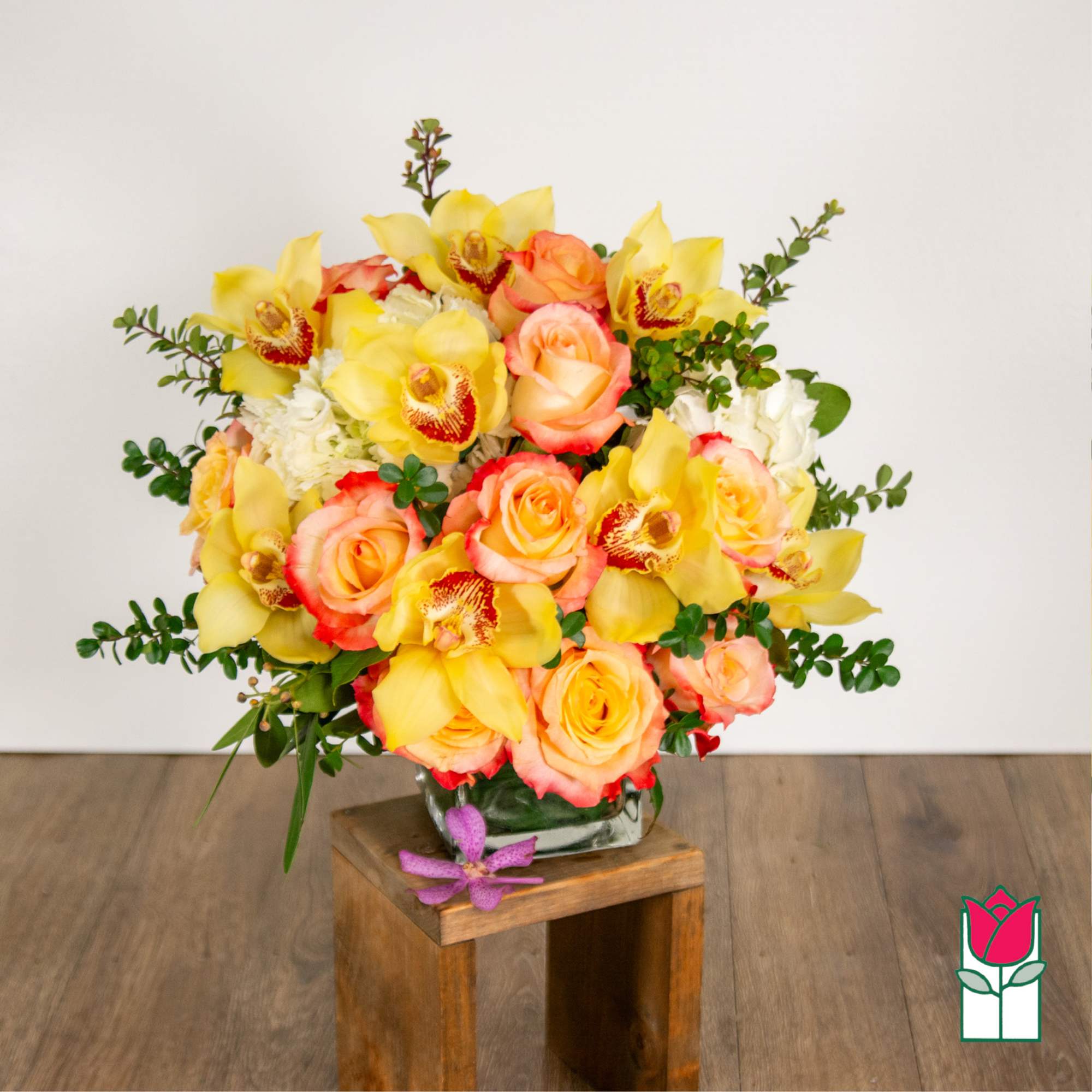 Bouquet of yellow orchids and peach roses in a glass vase