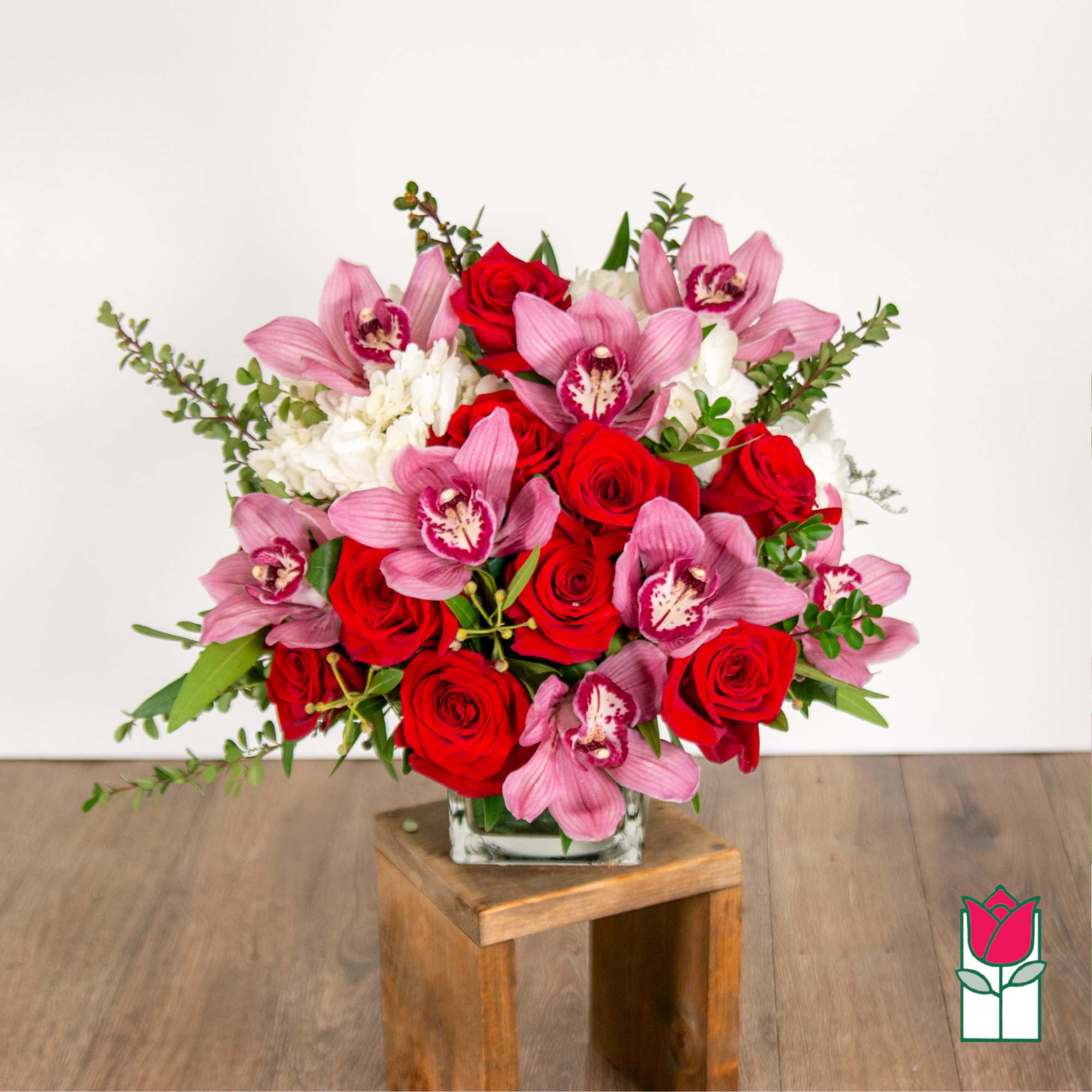 Bouquet of red roses and pink orchids in a glass vase