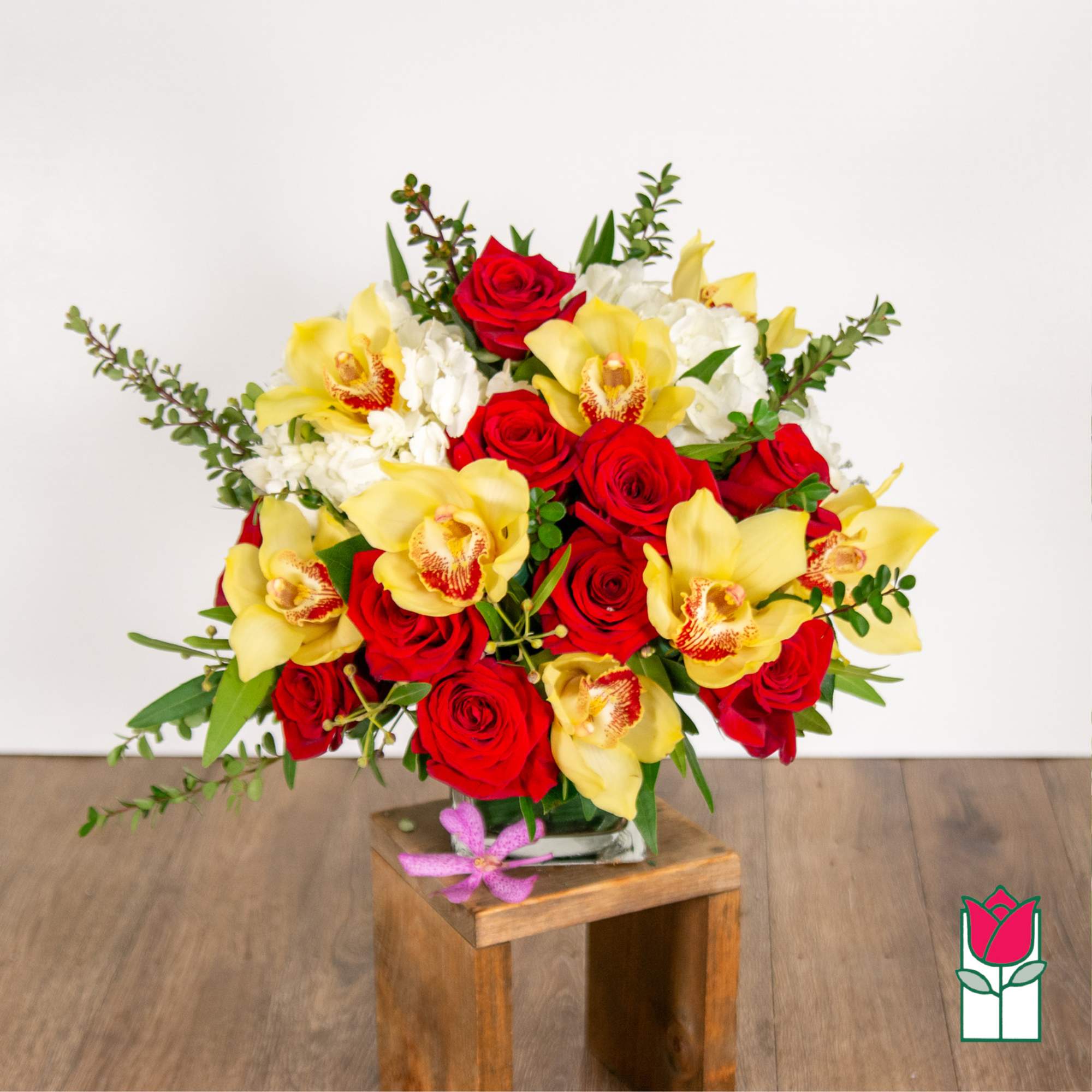 Bouquet of red roses and yellow orchids in a glass vase