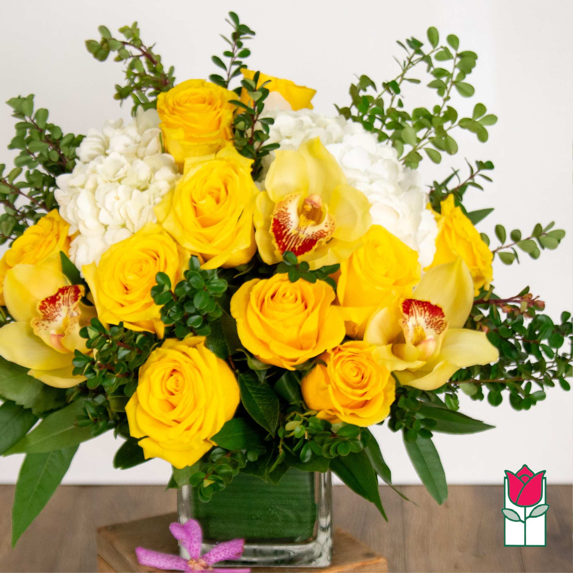Yellow roses and white orchids in a clear glass vase