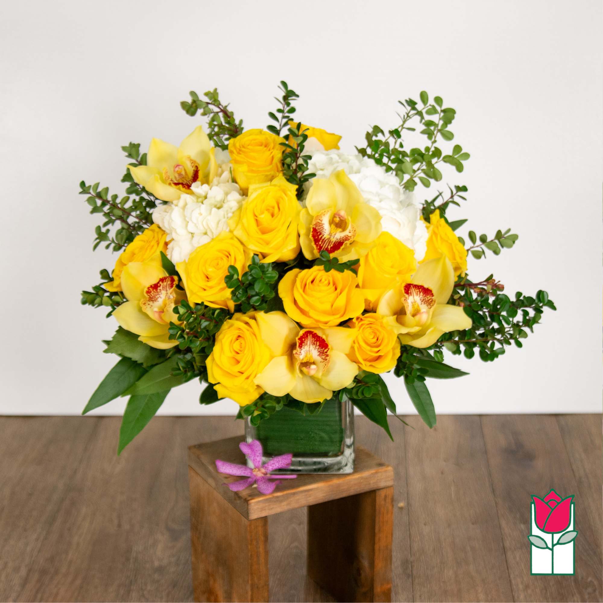 Yellow roses and orchids arranged in a glass vase
