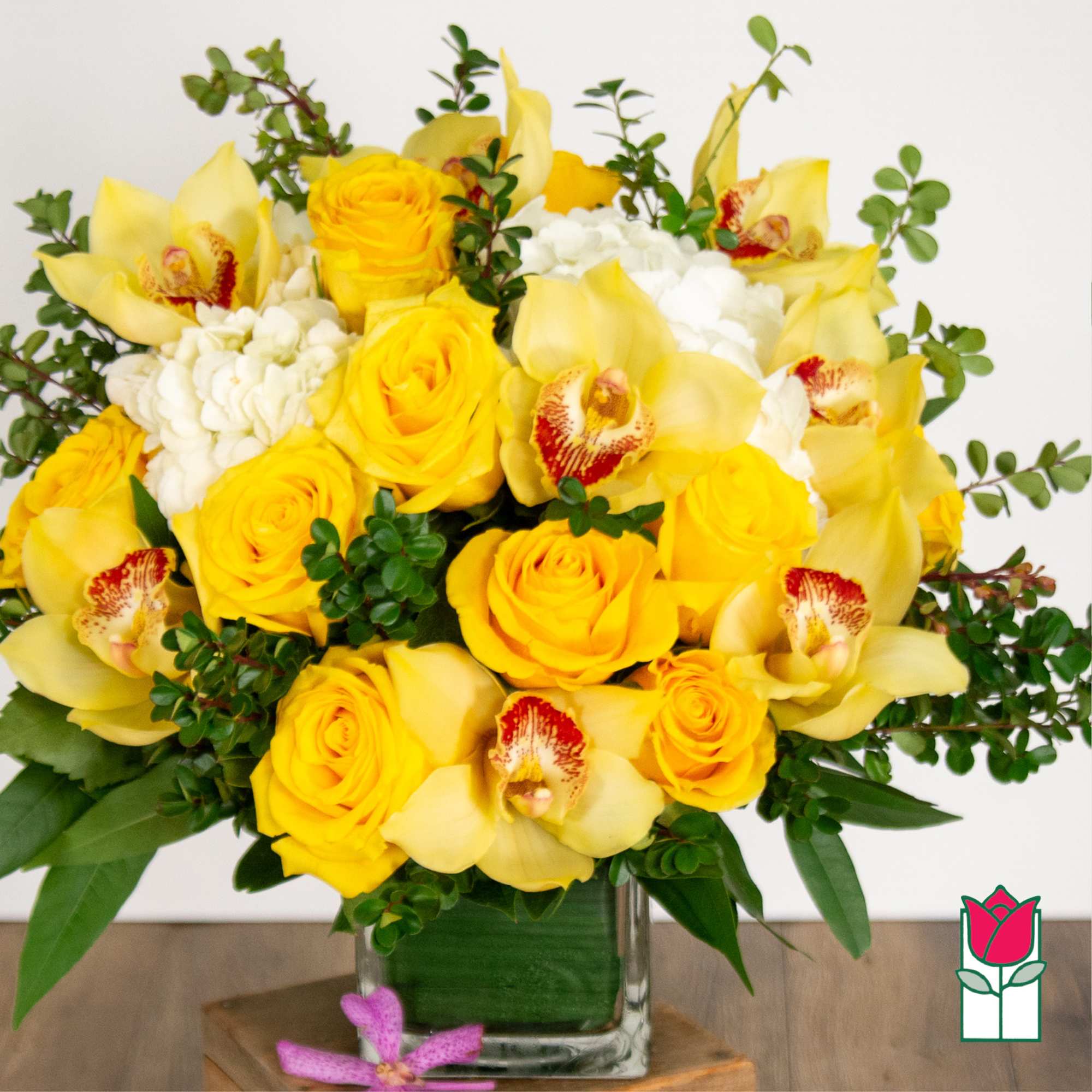 Yellow roses and orchids in a clear glass vase
