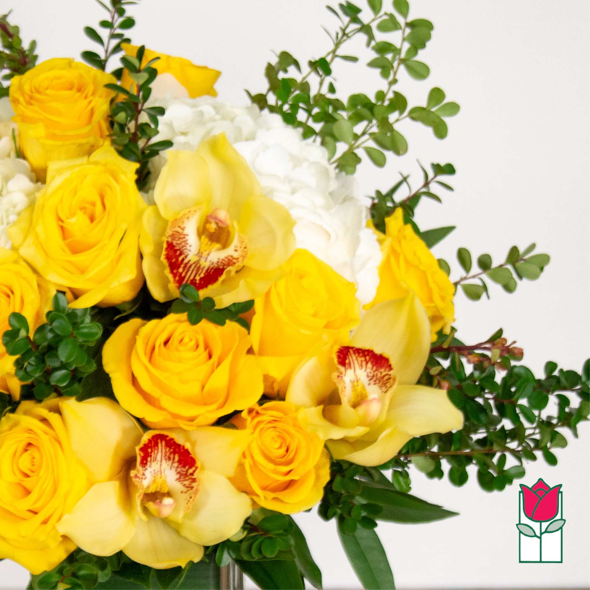 Yellow roses and pale orchids arranged with white blooms in a vase