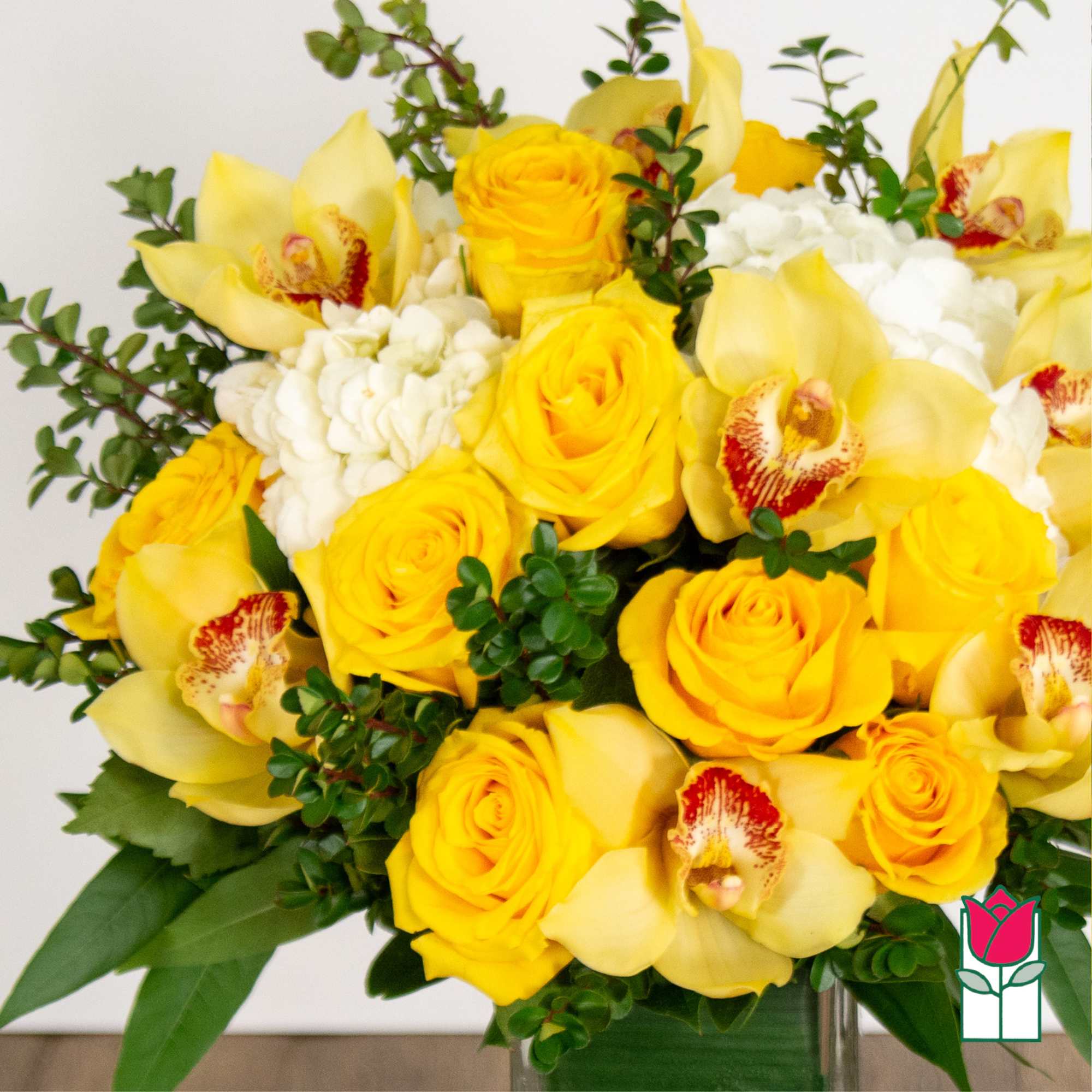 Yellow roses and orchids arranged in a glass vase