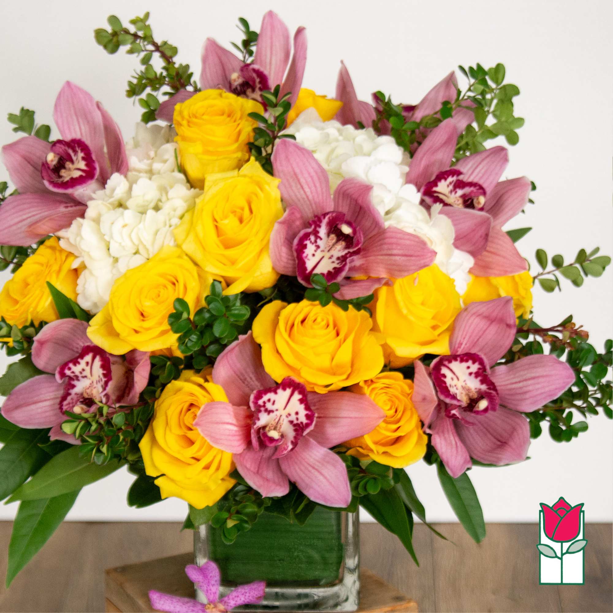 Yellow roses and pink orchids in a glass vase