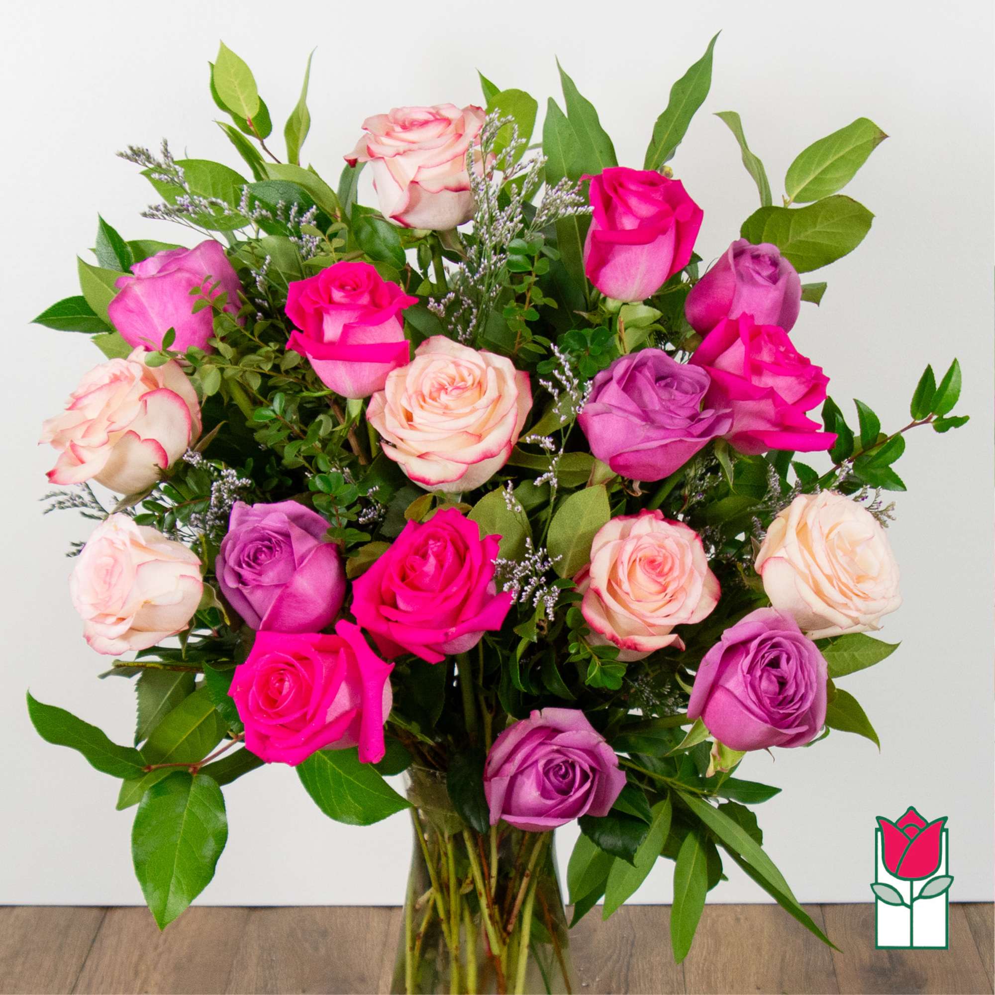 Bouquet of pink, purple, and cream roses in a clear glass vase
