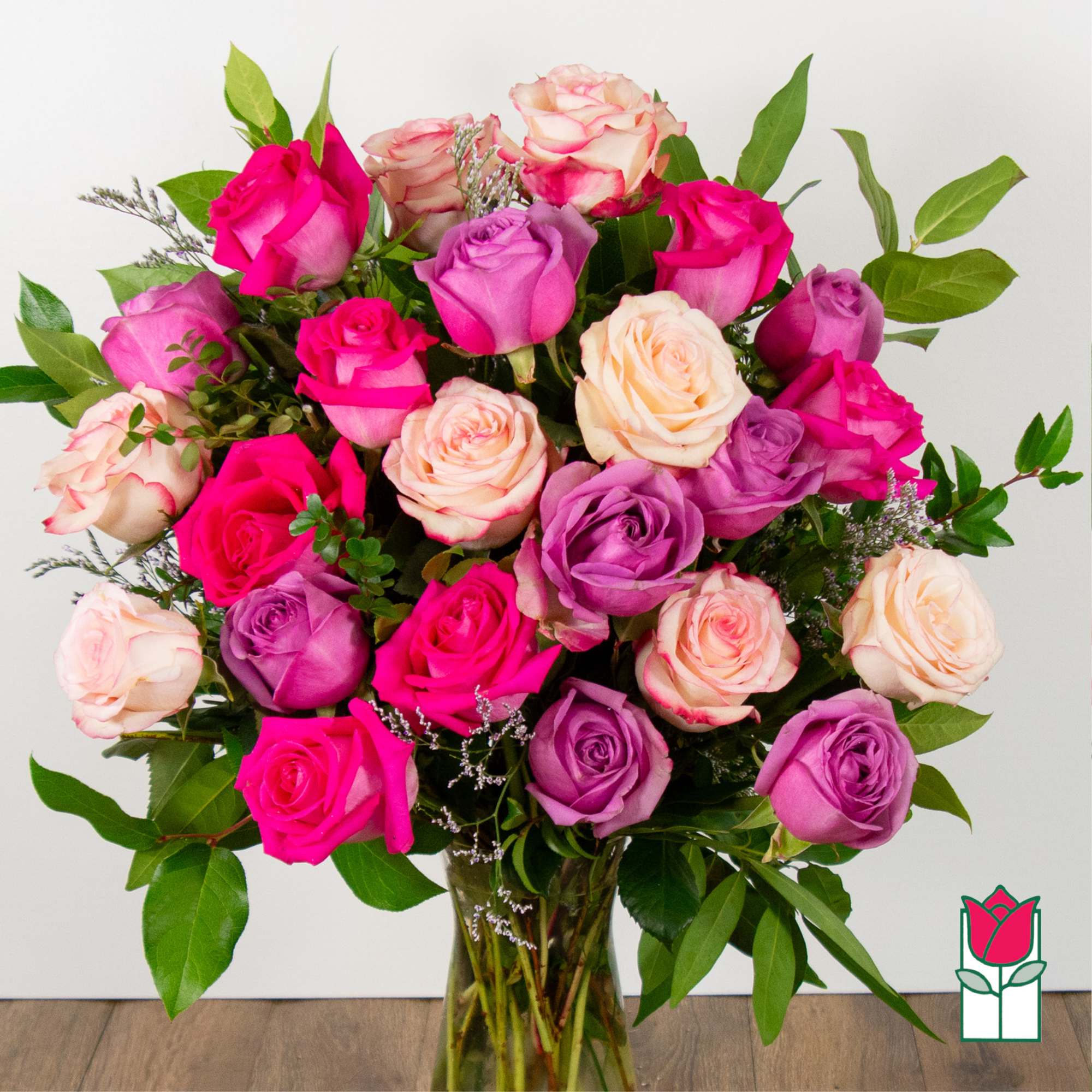 Bouquet of pink, purple, and cream roses in a glass vase
