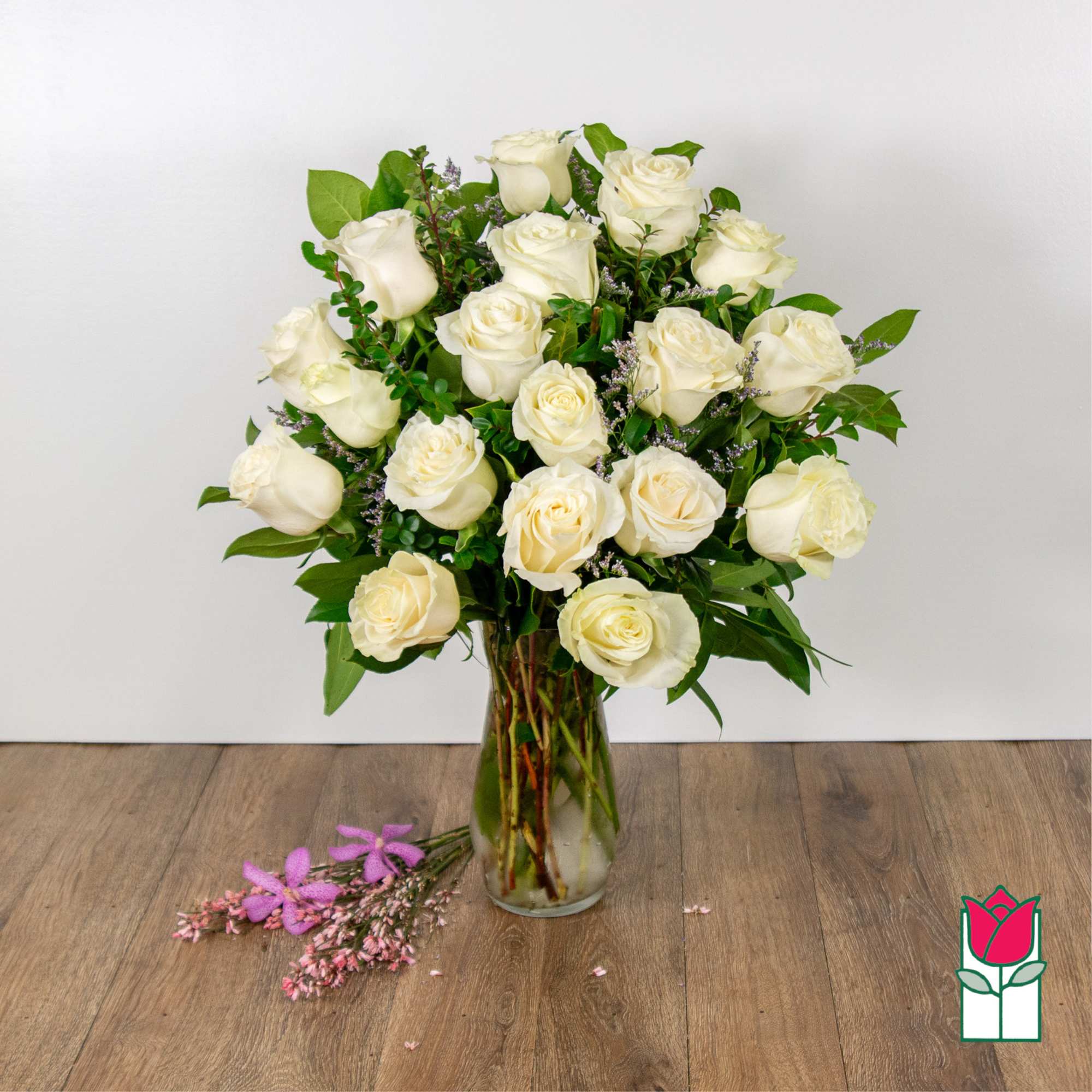 Bouquet of white roses in a clear glass vase with greenery