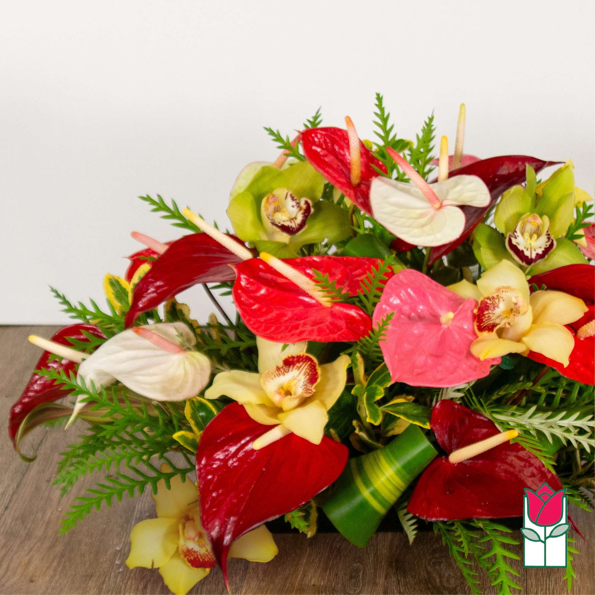 Arrangement of red, pink, white, and green orchids in a low design