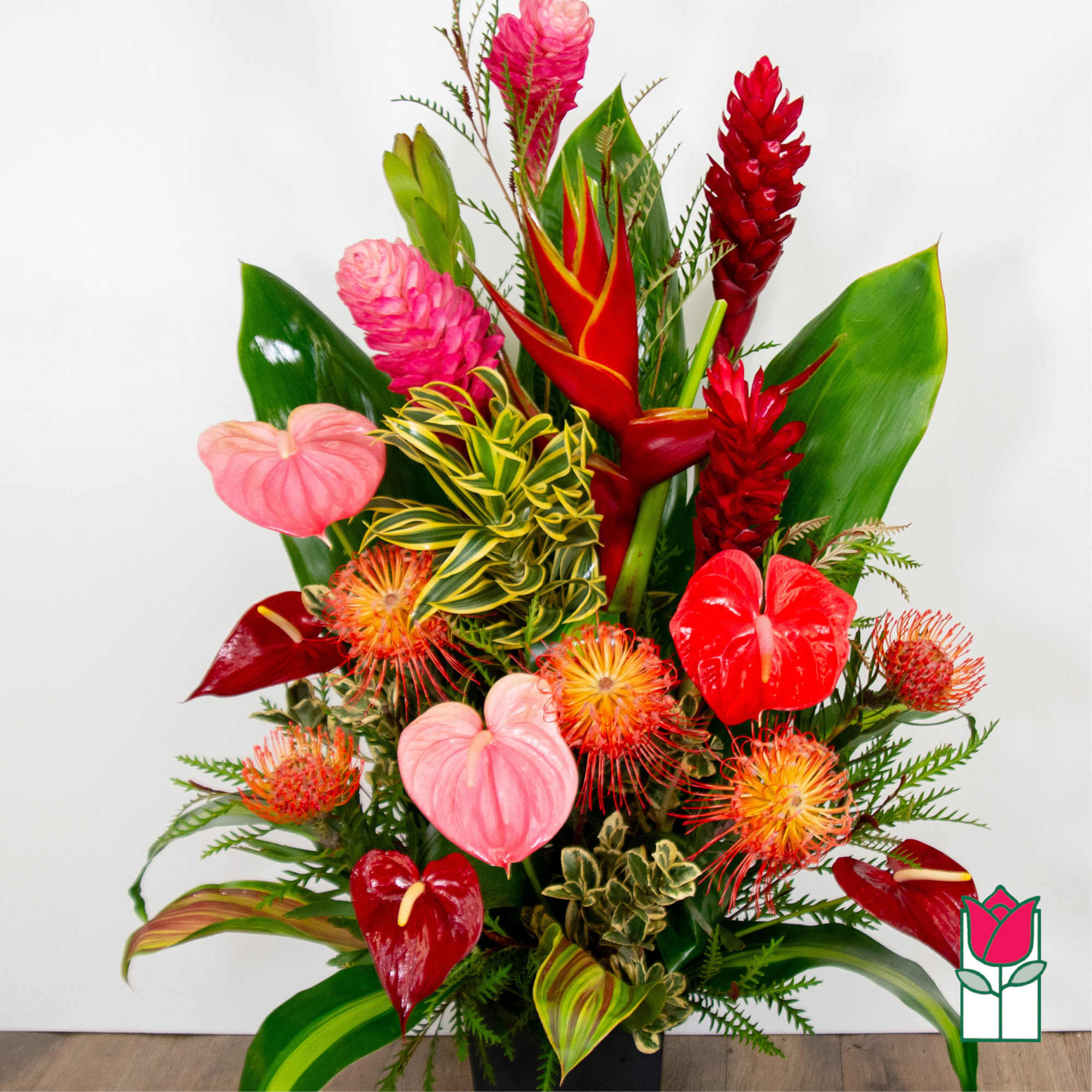 Tropical arrangement with red and pink blooms in a black container