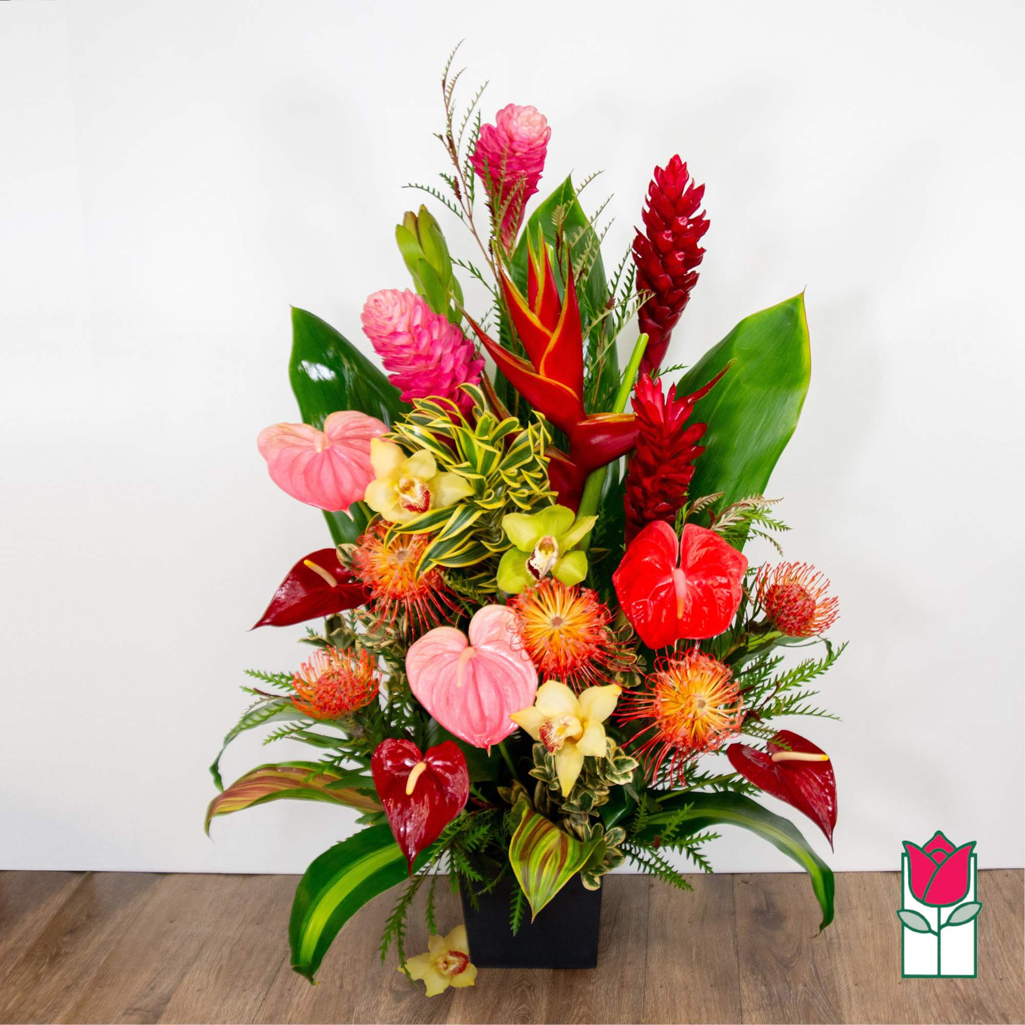 Tropical flower arrangement with red anthuriums and pink blooms in a black vase