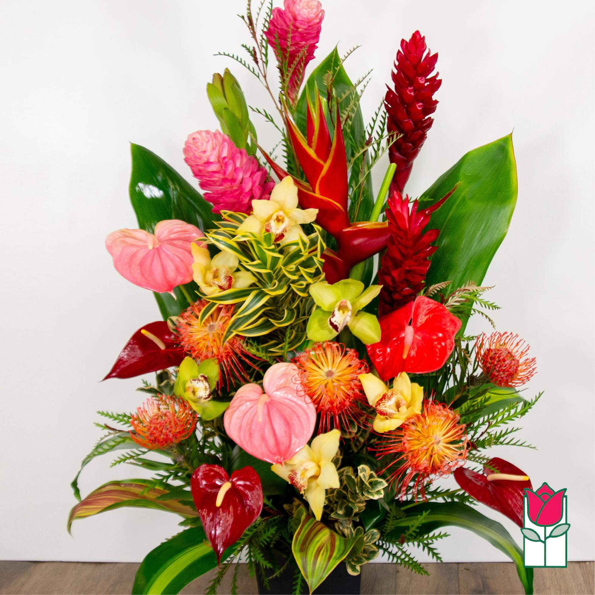 Tropical arrangement with red and pink flowers in a black container