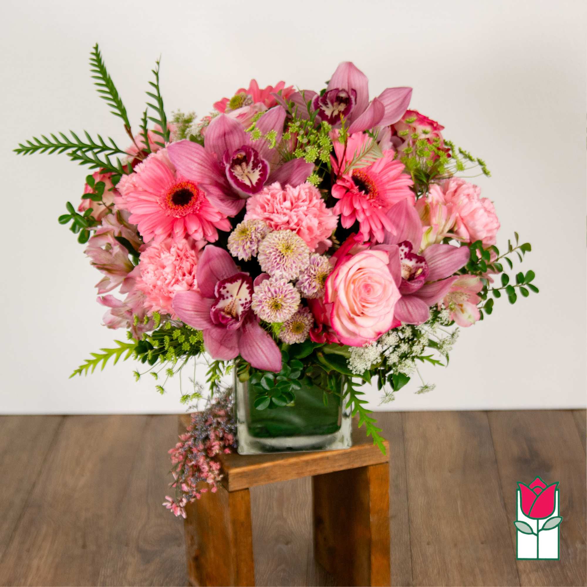 Pink mixed flower arrangement in a square glass vase
