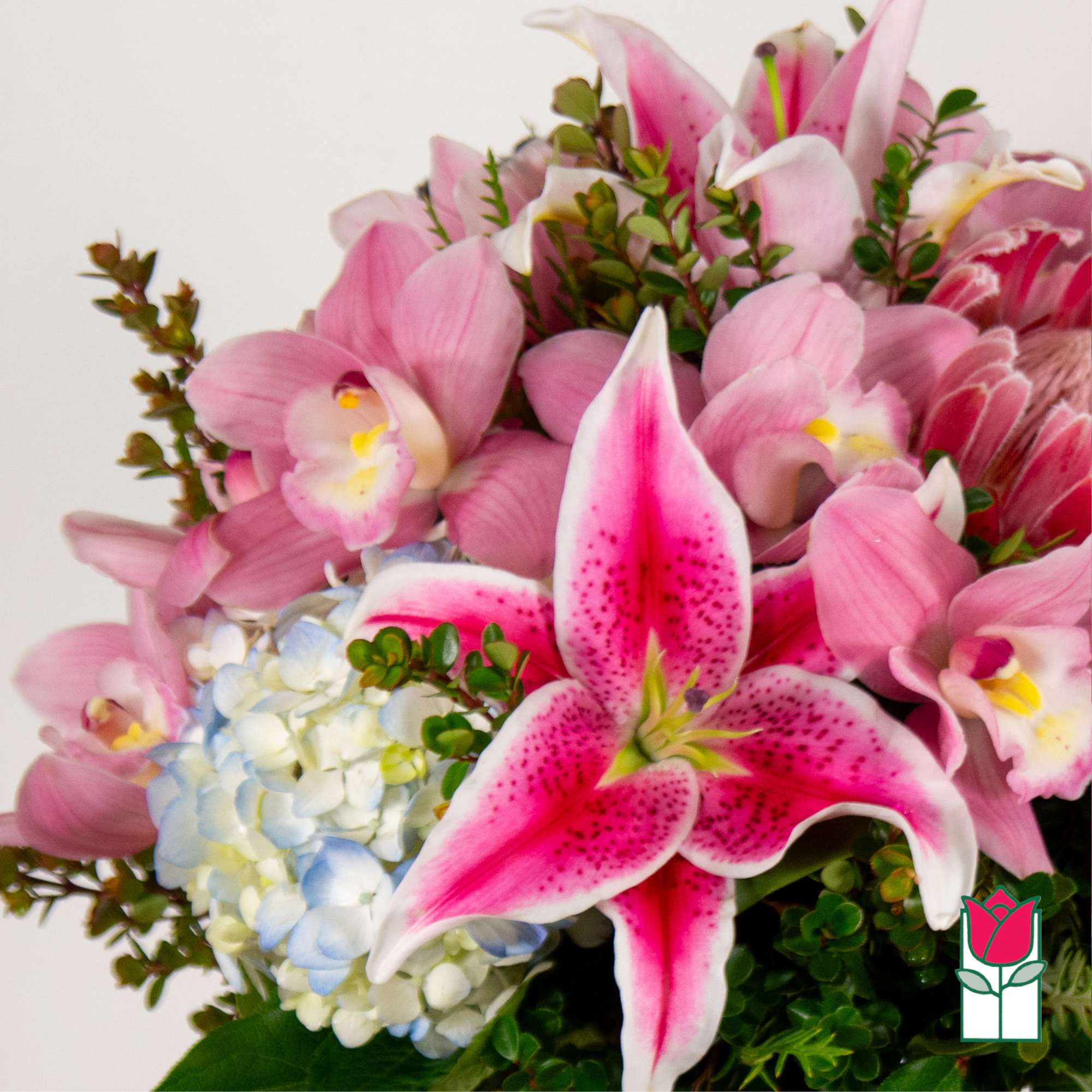 Pink lilies and orchids with a pale blue hydrangea cluster