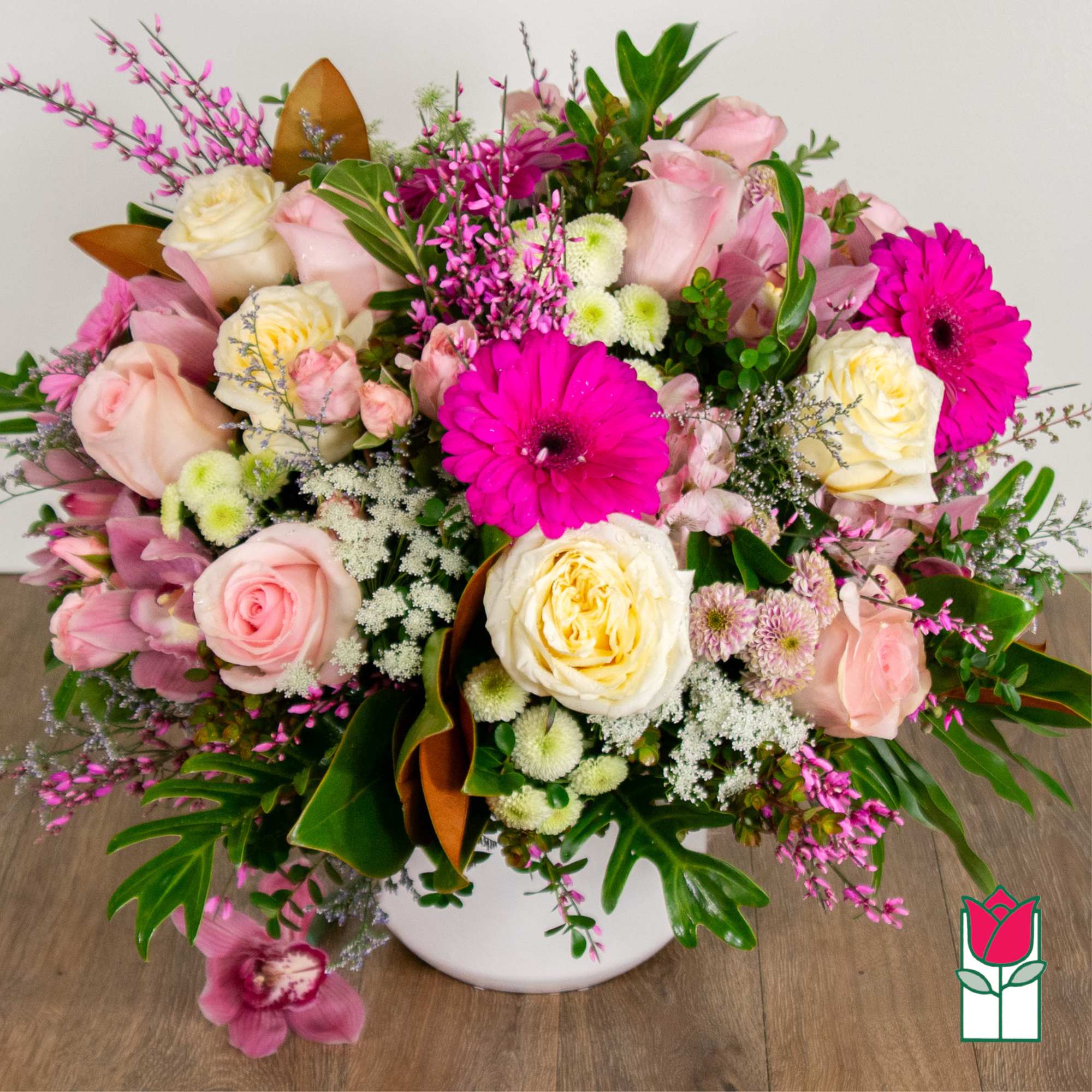Pink and cream rose bouquet with bright magenta gerbera daisies in a white vase
