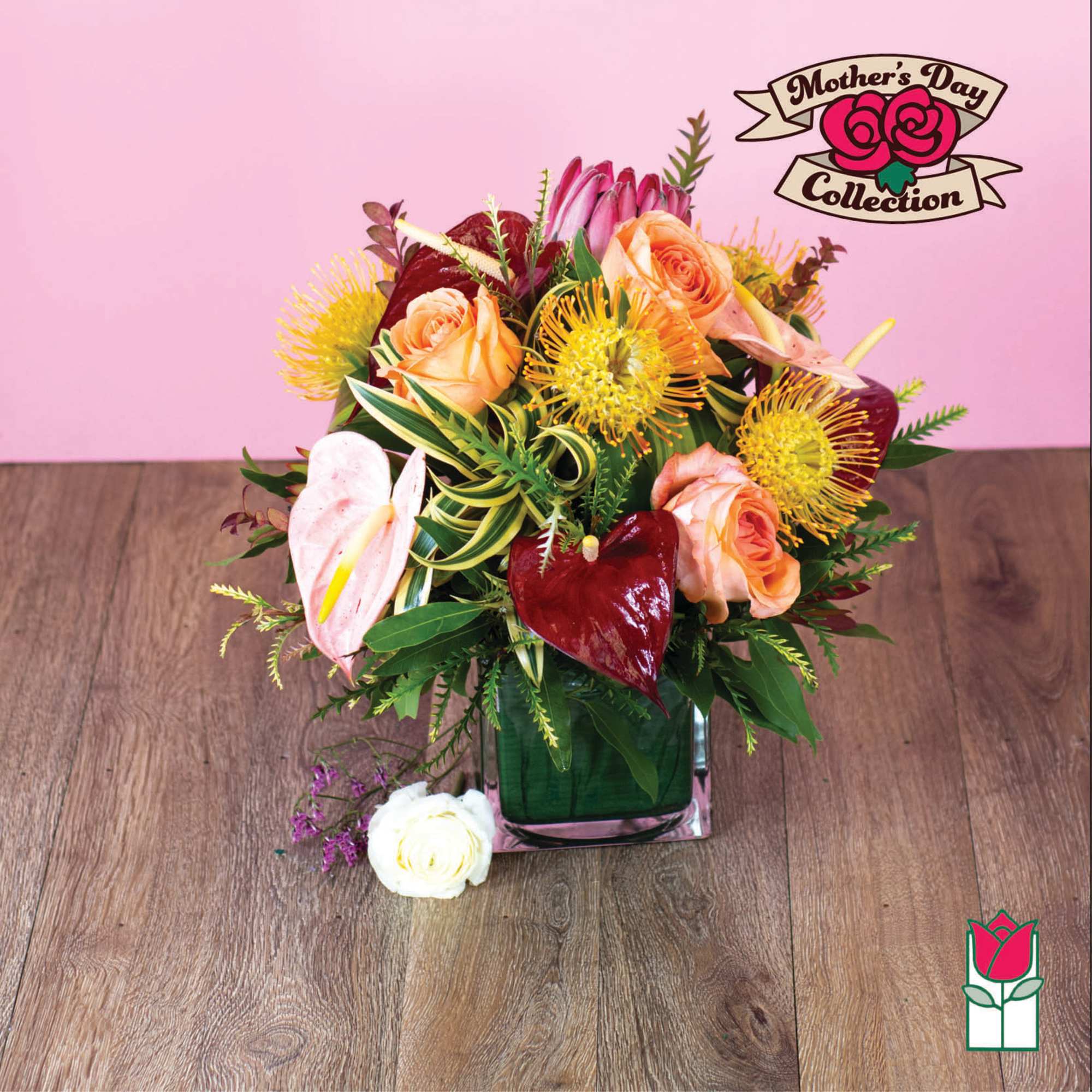 Pink and peach floral arrangement in a square glass vase