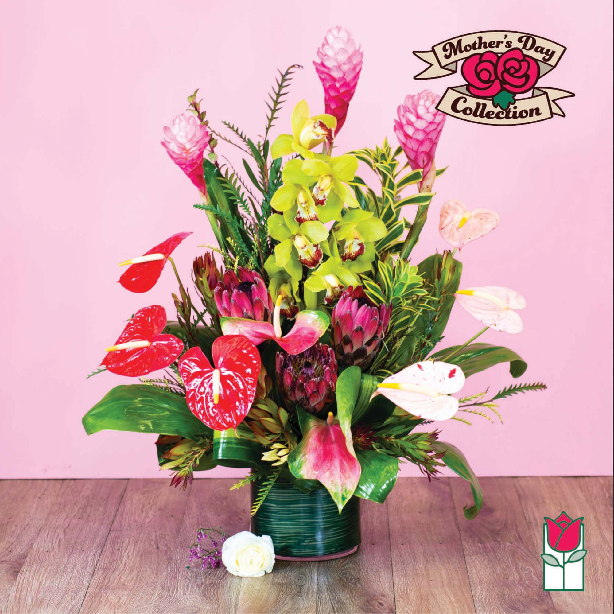 Tropical floral arrangement with pink and red blooms in a green vase