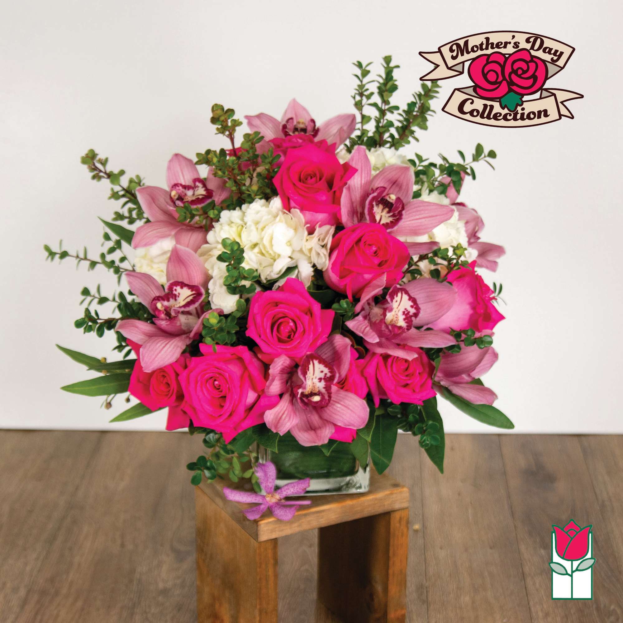 Compact arrangement of hot pink roses, pink orchids, and white blooms in a clear glass vase