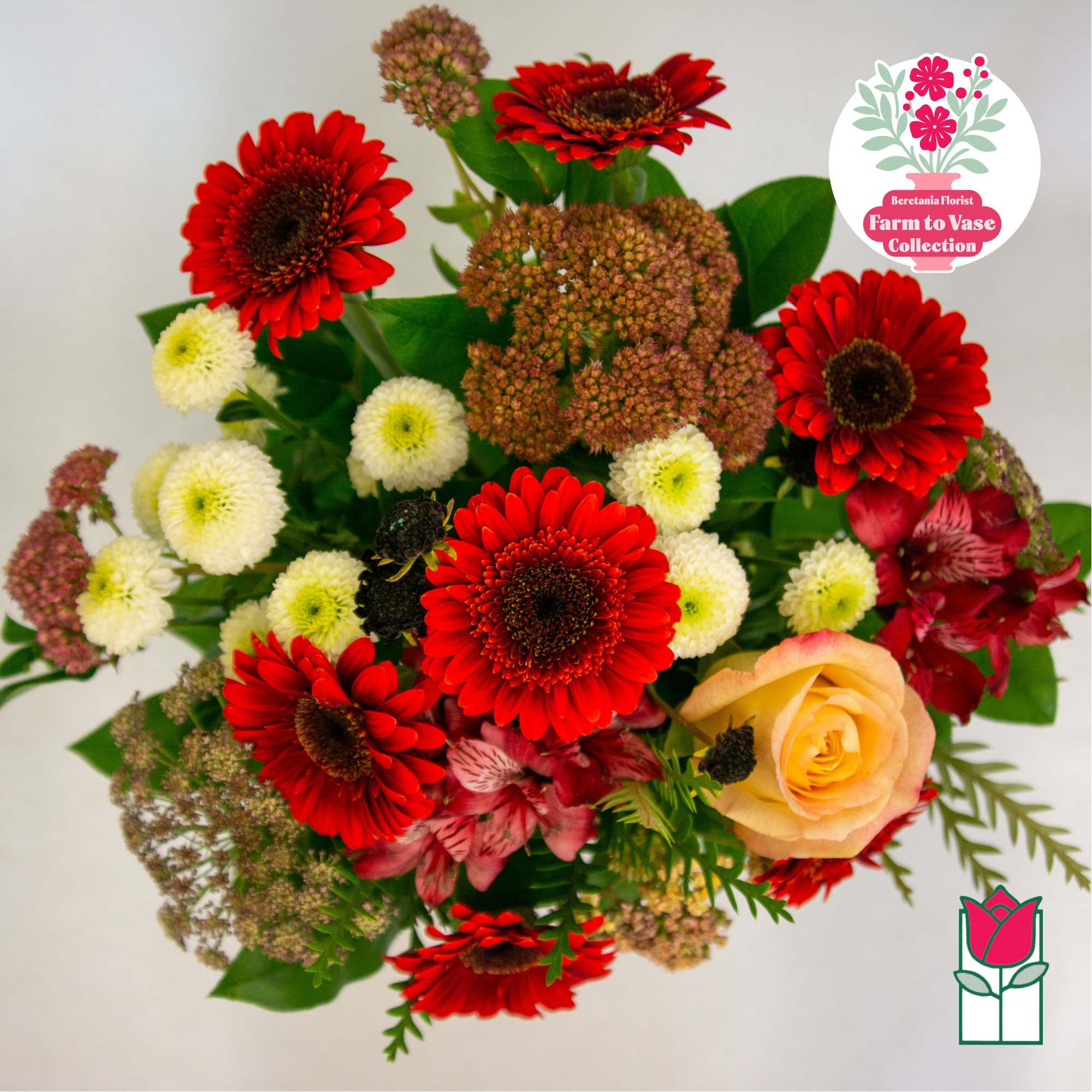 Mixed bouquet with red gerbera daisies, a peach rose, and small white blooms