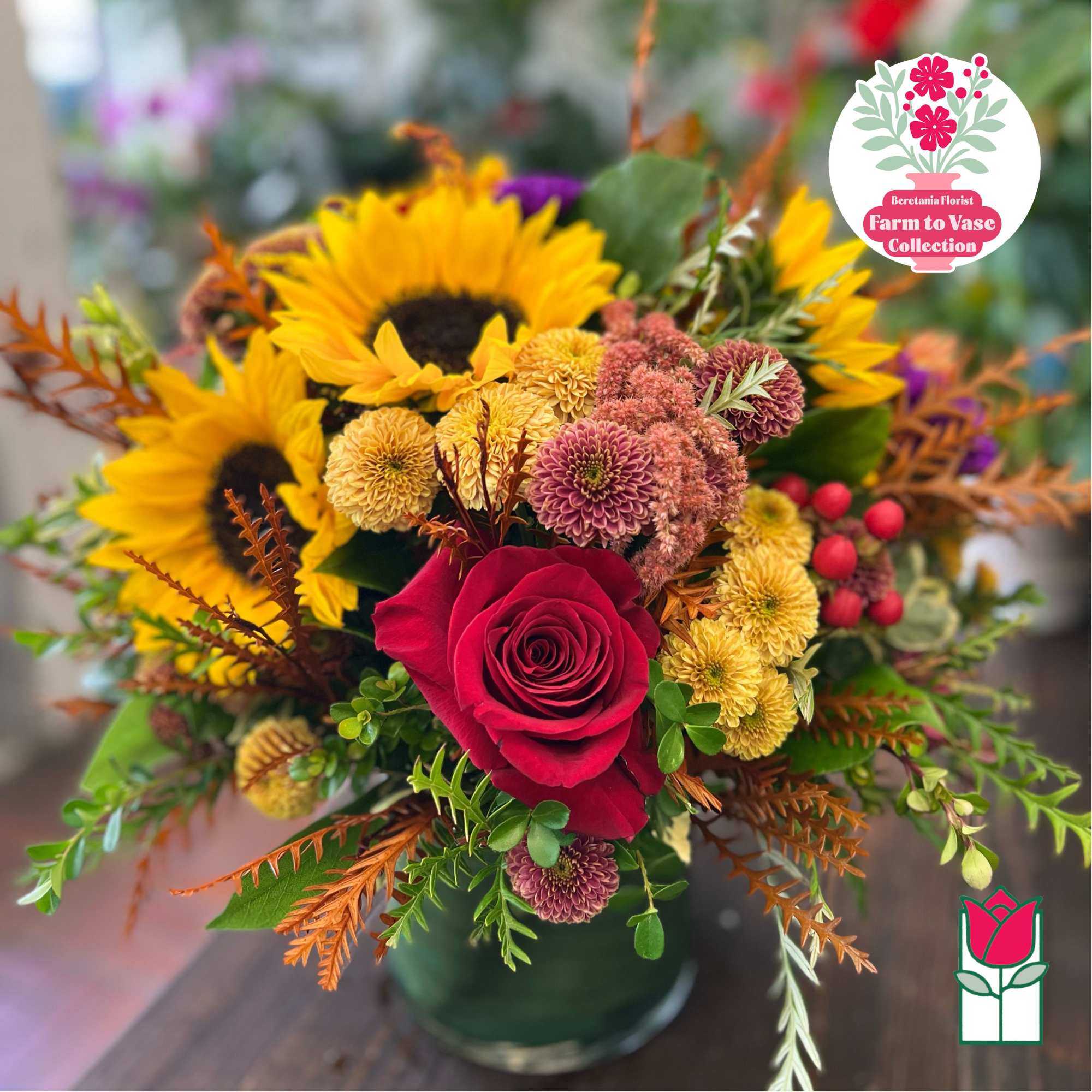 Bouquet with sunflowers, a red rose, and mixed mums in a glass vase