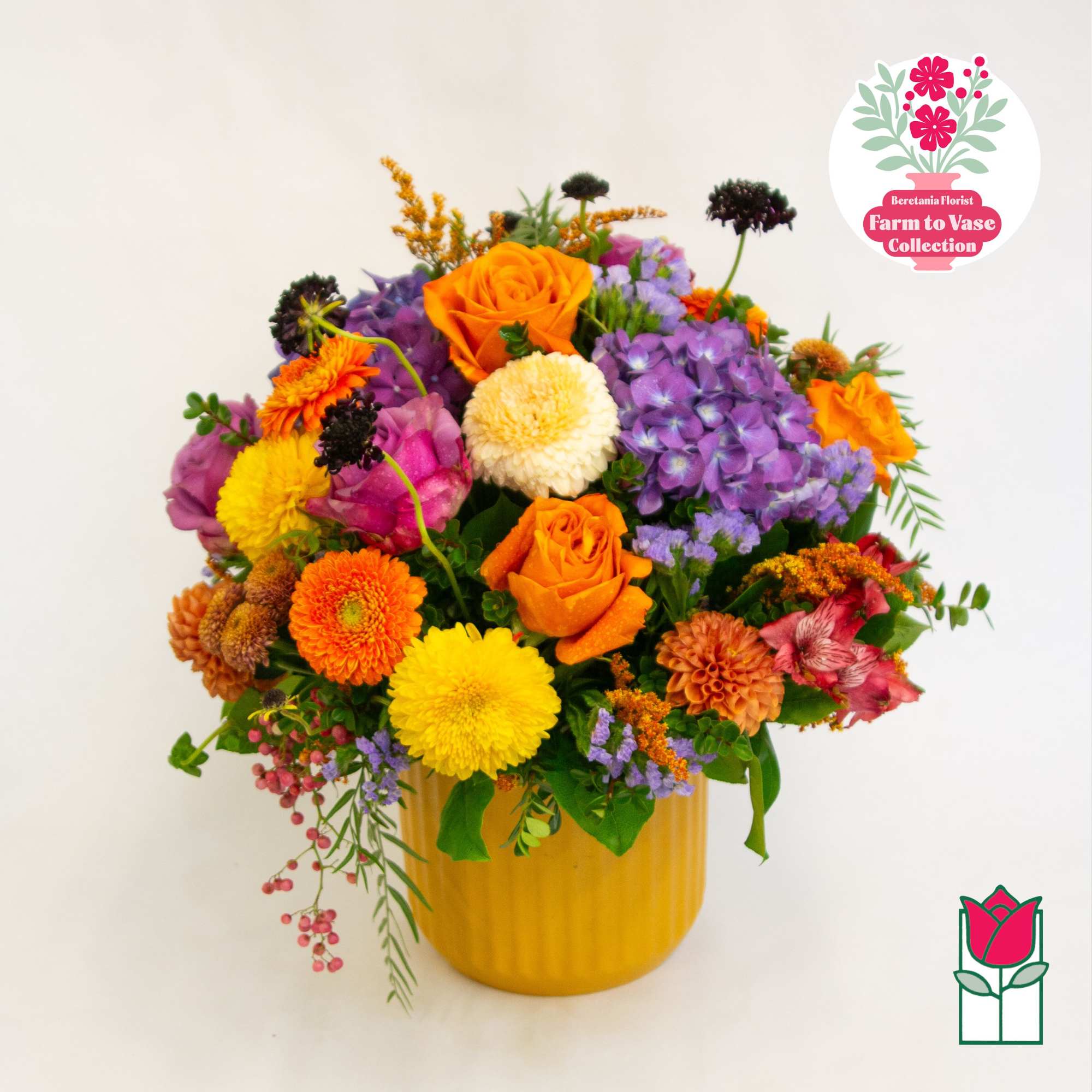 Colorful mixed bouquet in a yellow vase with orange roses and purple blooms