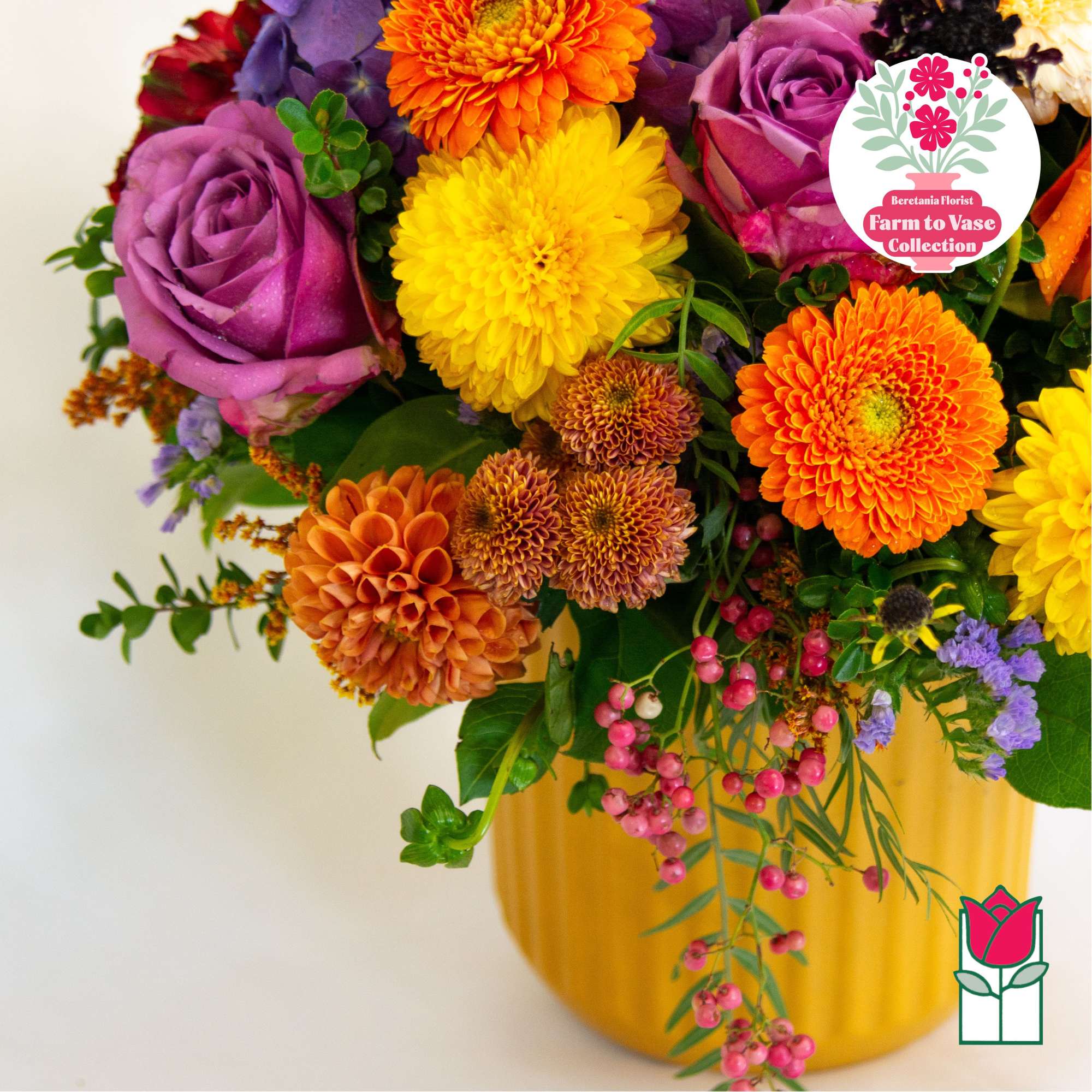 Mixed bouquet of purple, yellow, and orange flowers in a yellow vase