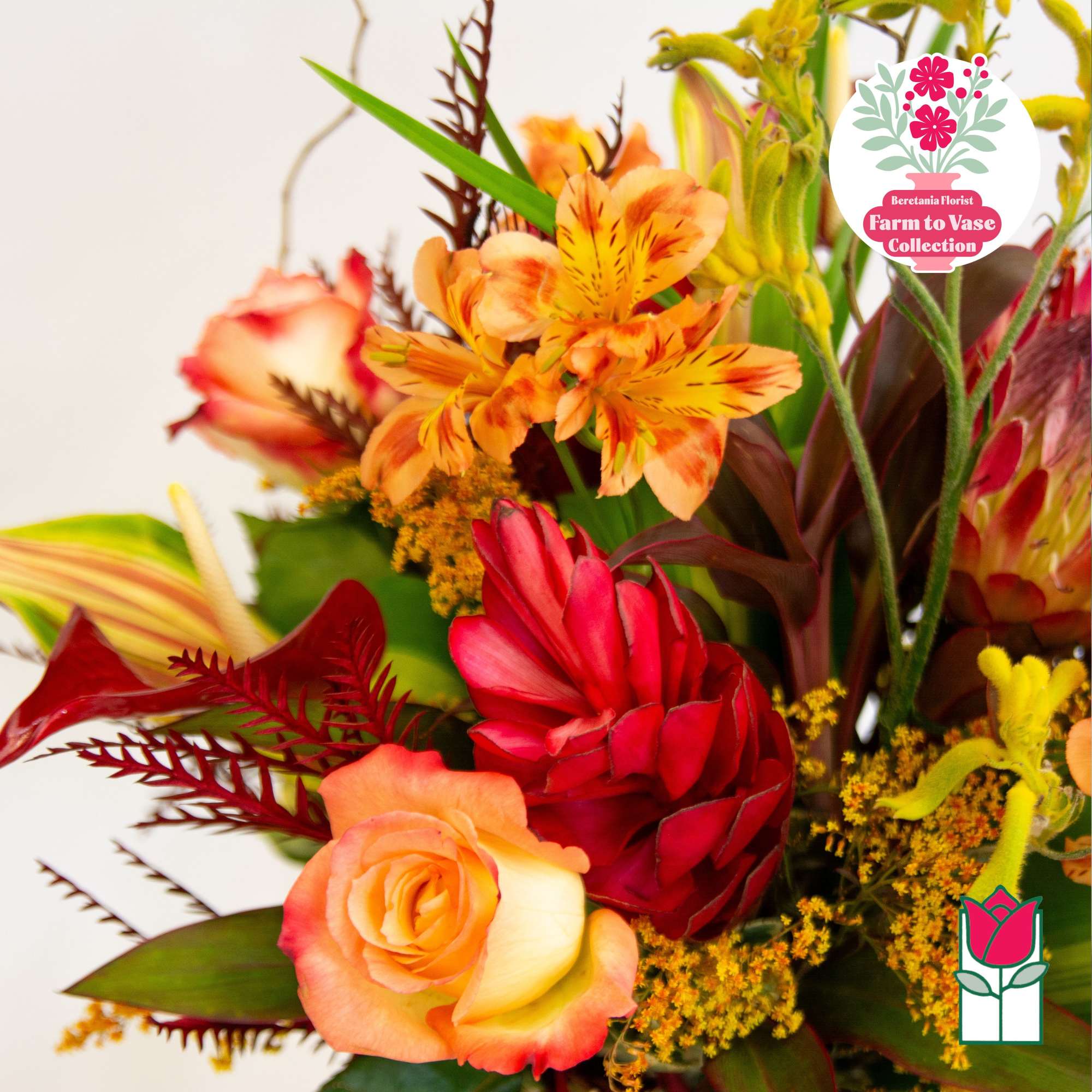 Bright bouquet with orange and red flowers, including roses and alstroemeria.