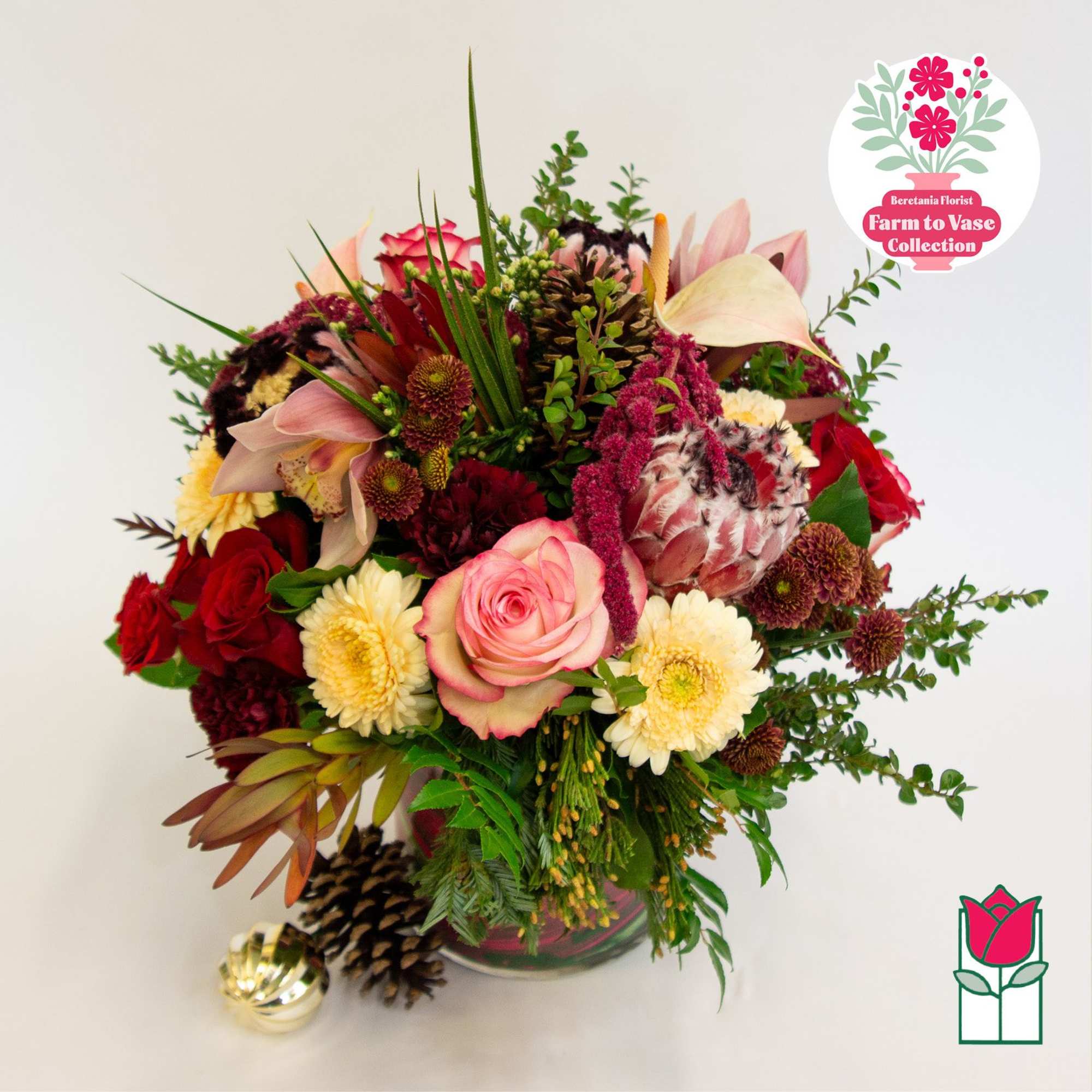 Mixed bouquet of pink, red, and cream flowers in a glass vase