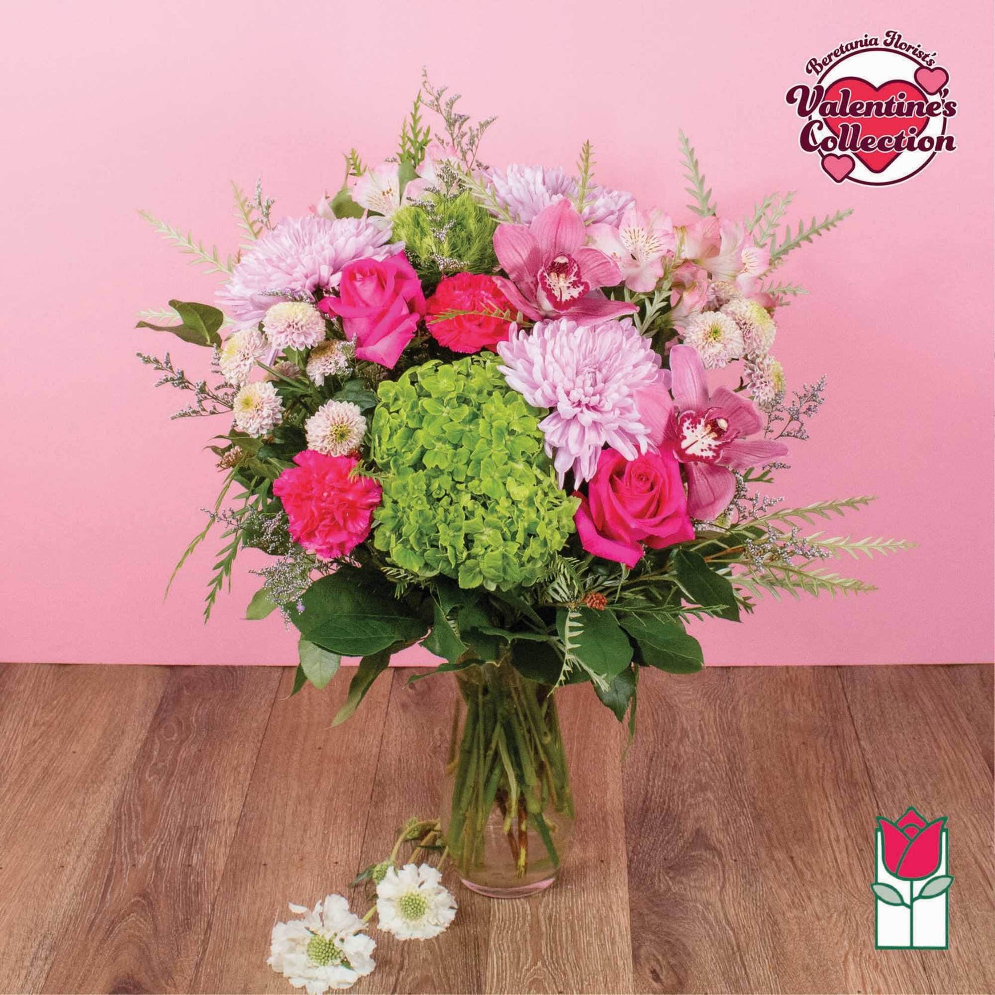 Pink and green mixed bouquet in a glass vase with roses and orchids
