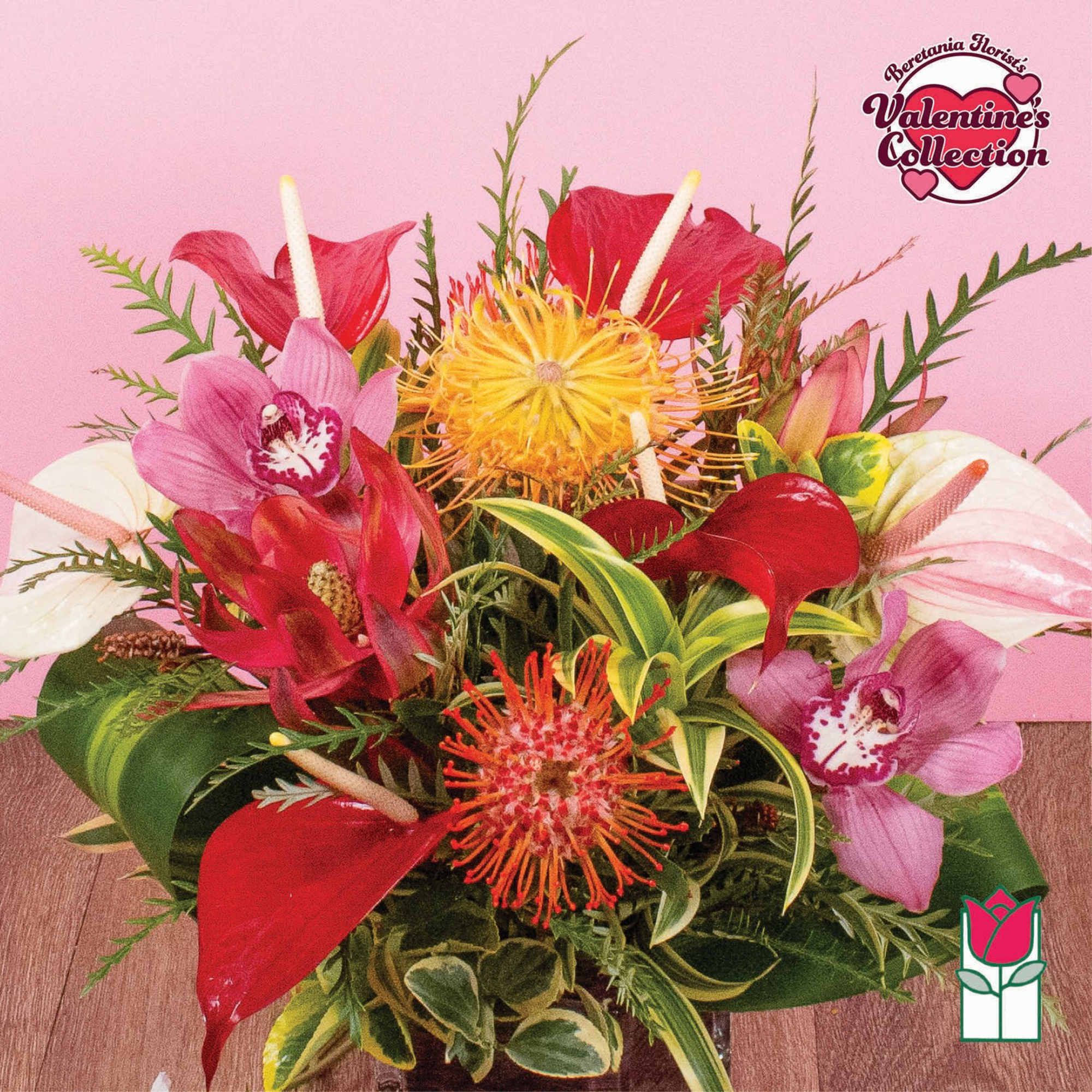 Tropical arrangement with red anthurium, pink orchids, and yellow pincushion protea in a low vase.