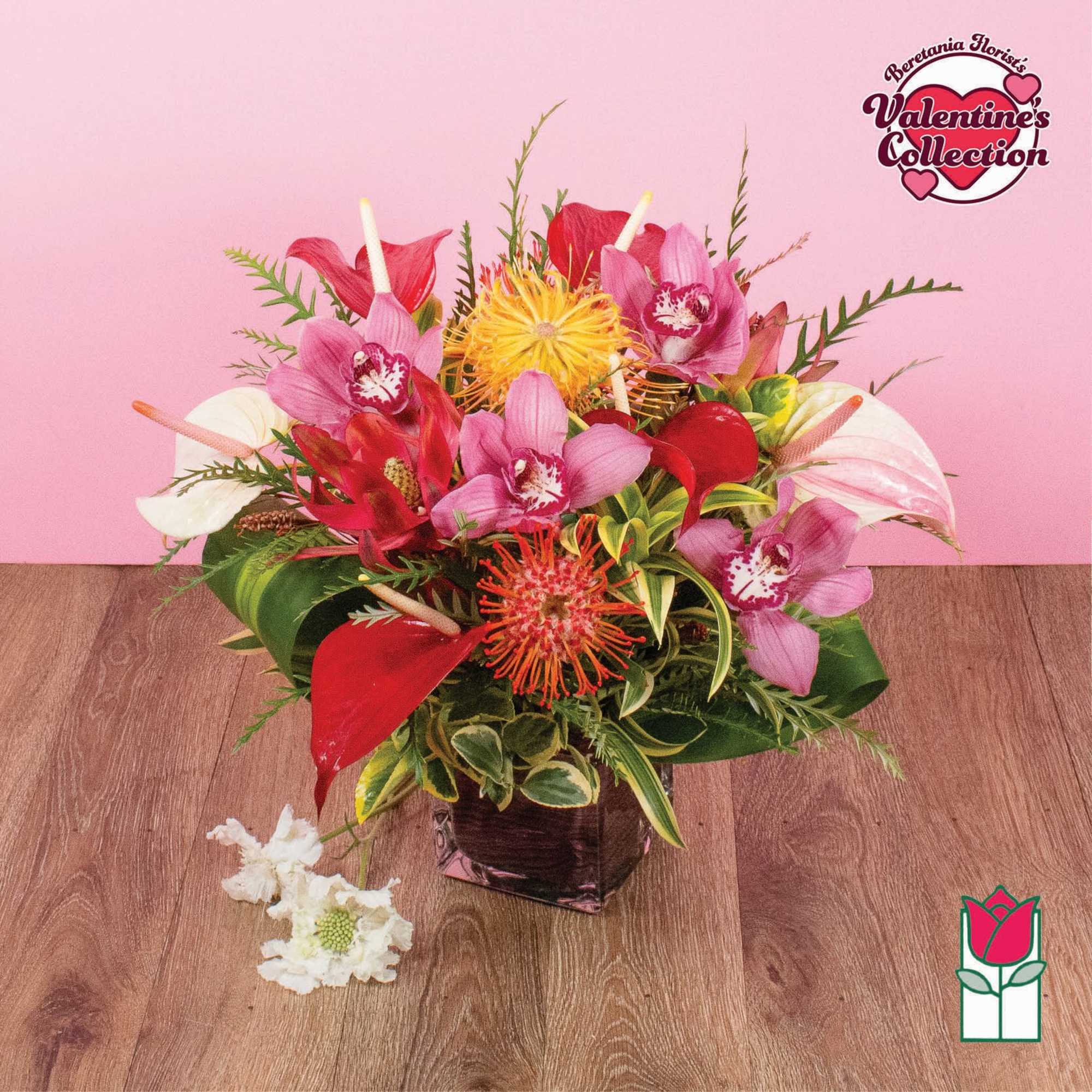 Tropical arrangement with pink orchids, red anthuriums, and orange protea in a square glass vase
