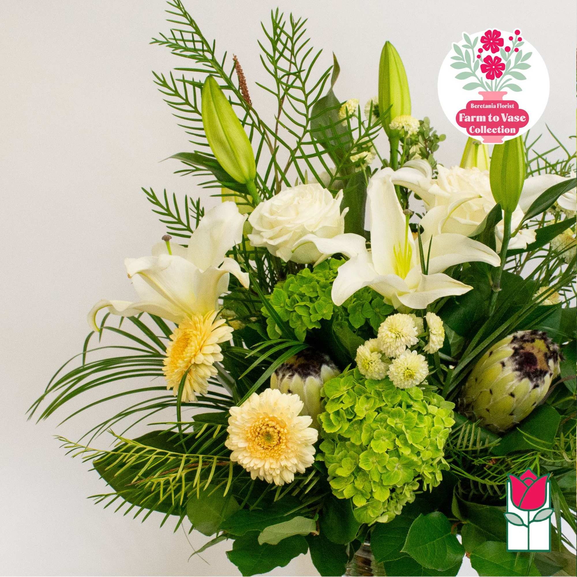White lilies and cream flowers arranged with green hydrangea in a vase