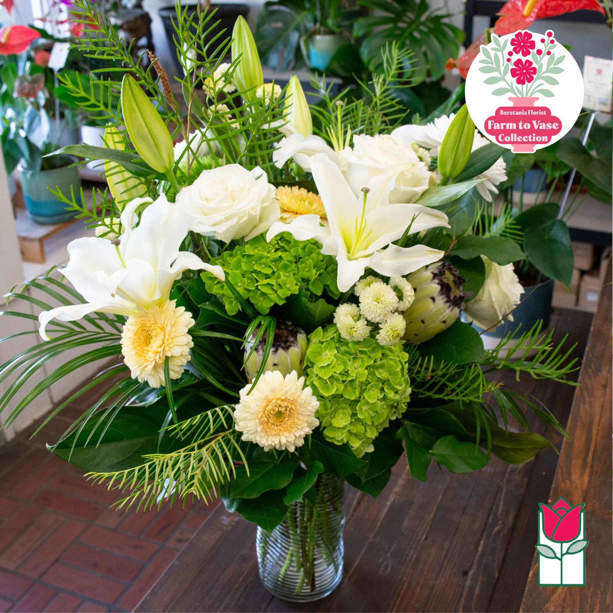 White lilies and roses in a glass vase with green hydrangeas