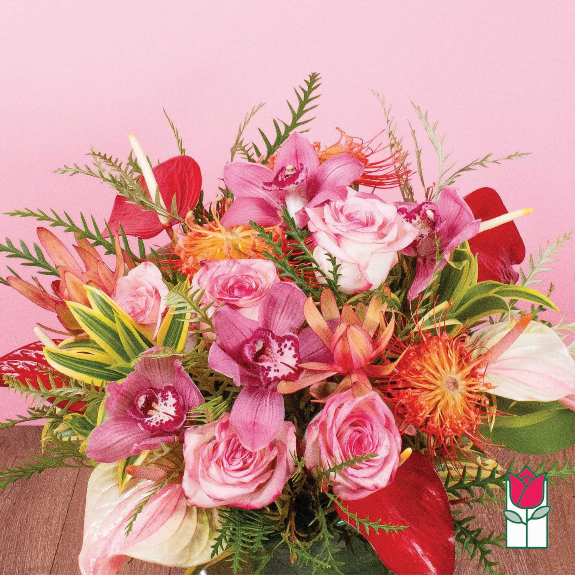 Vibrant arrangement of pink roses, orchids, and tropical blooms in a glass vase
