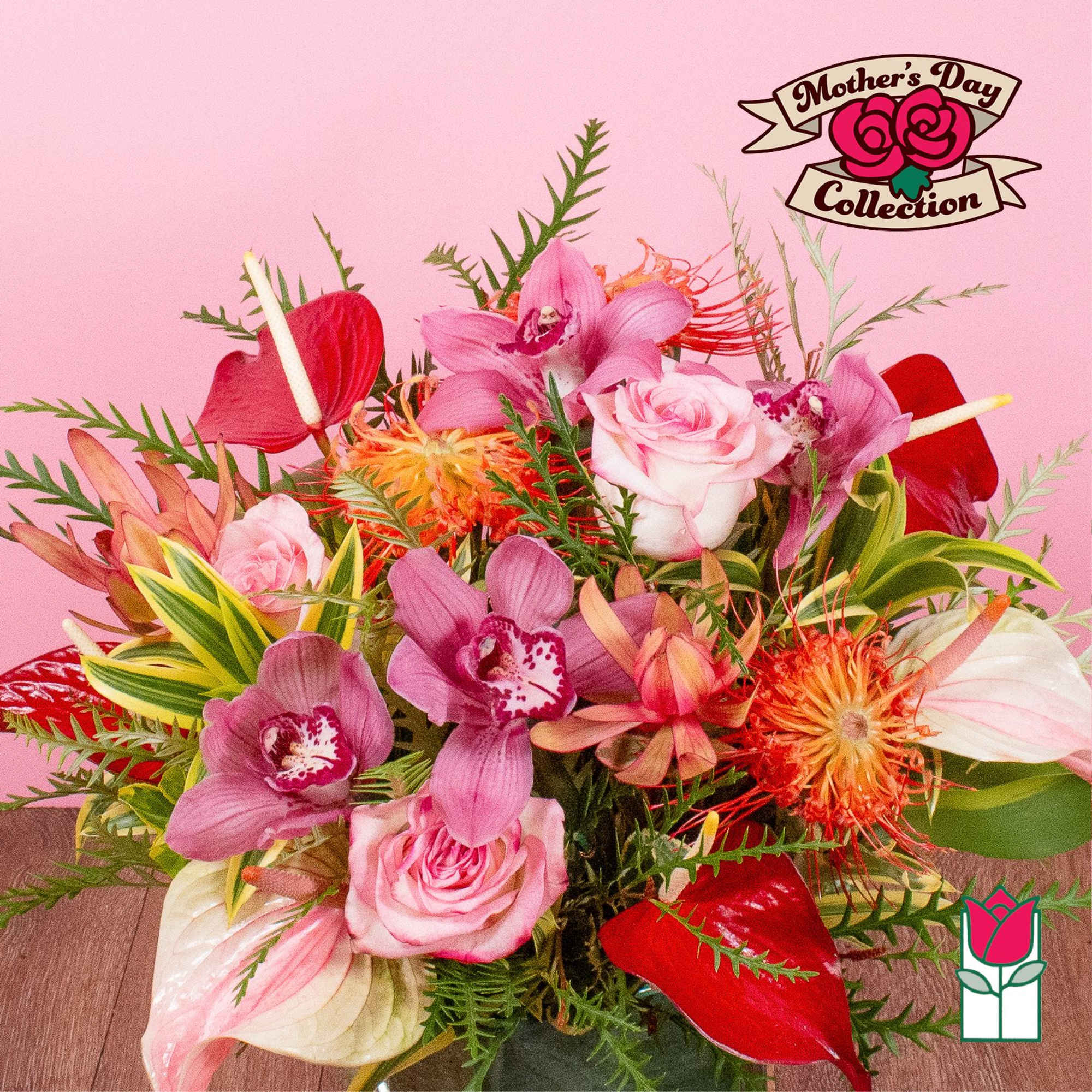 Colorful bouquet of pink roses, orchids, anthuriums, and orange blooms in a vase on a pink background