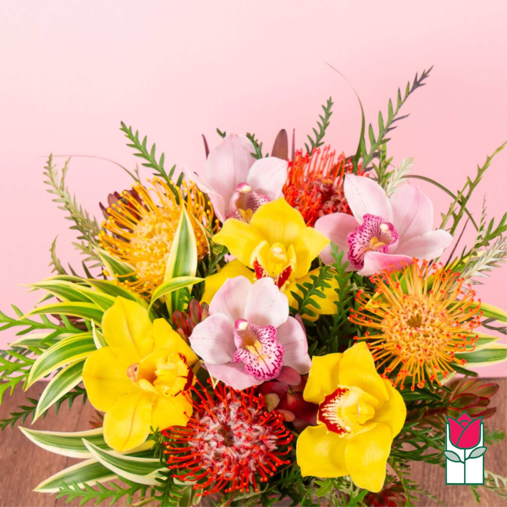 Bright bouquet of yellow and pink orchids with orange pincushion blooms against a pink background