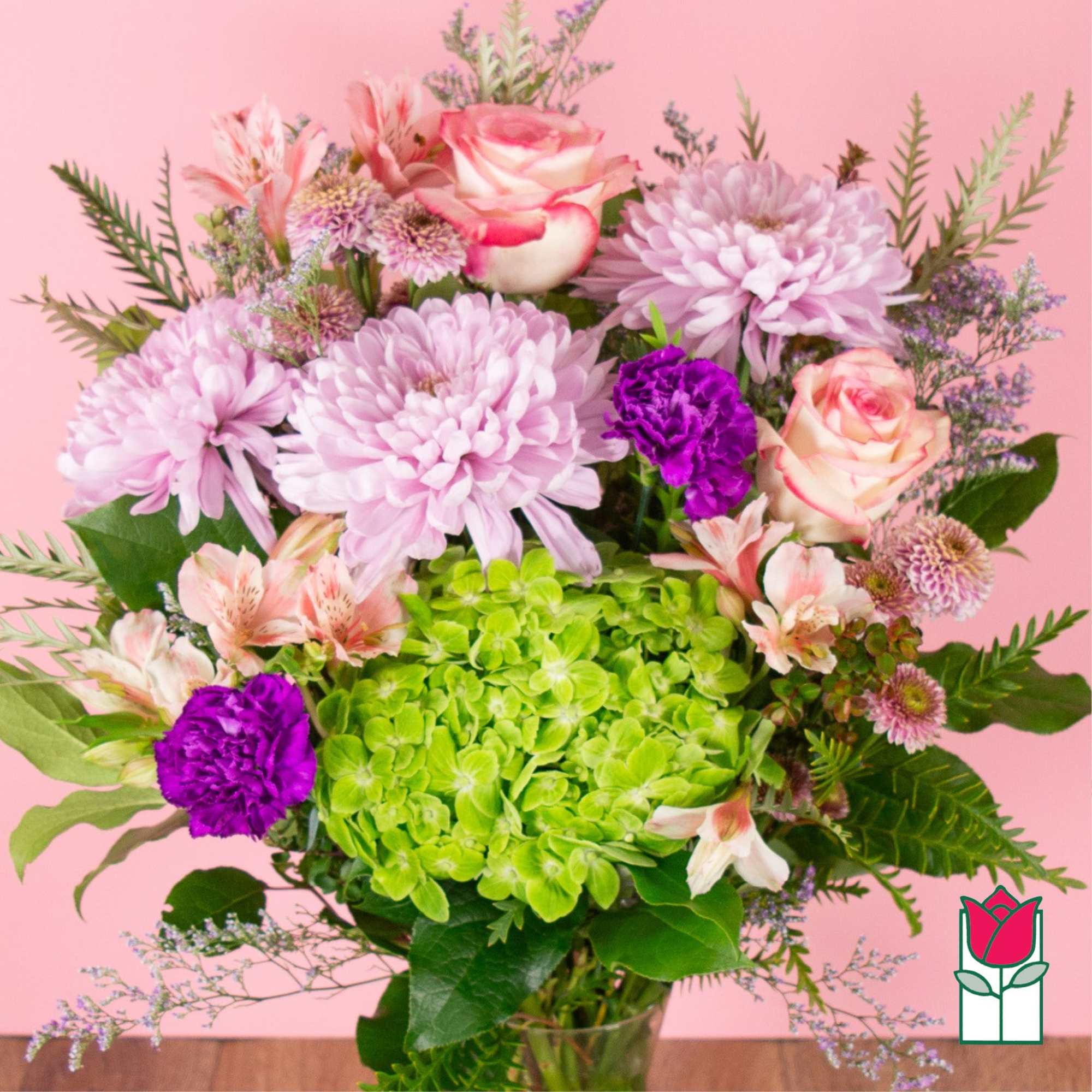 Pink and purple bouquet with roses, chrysanthemums, and hydrangea in a glass vase