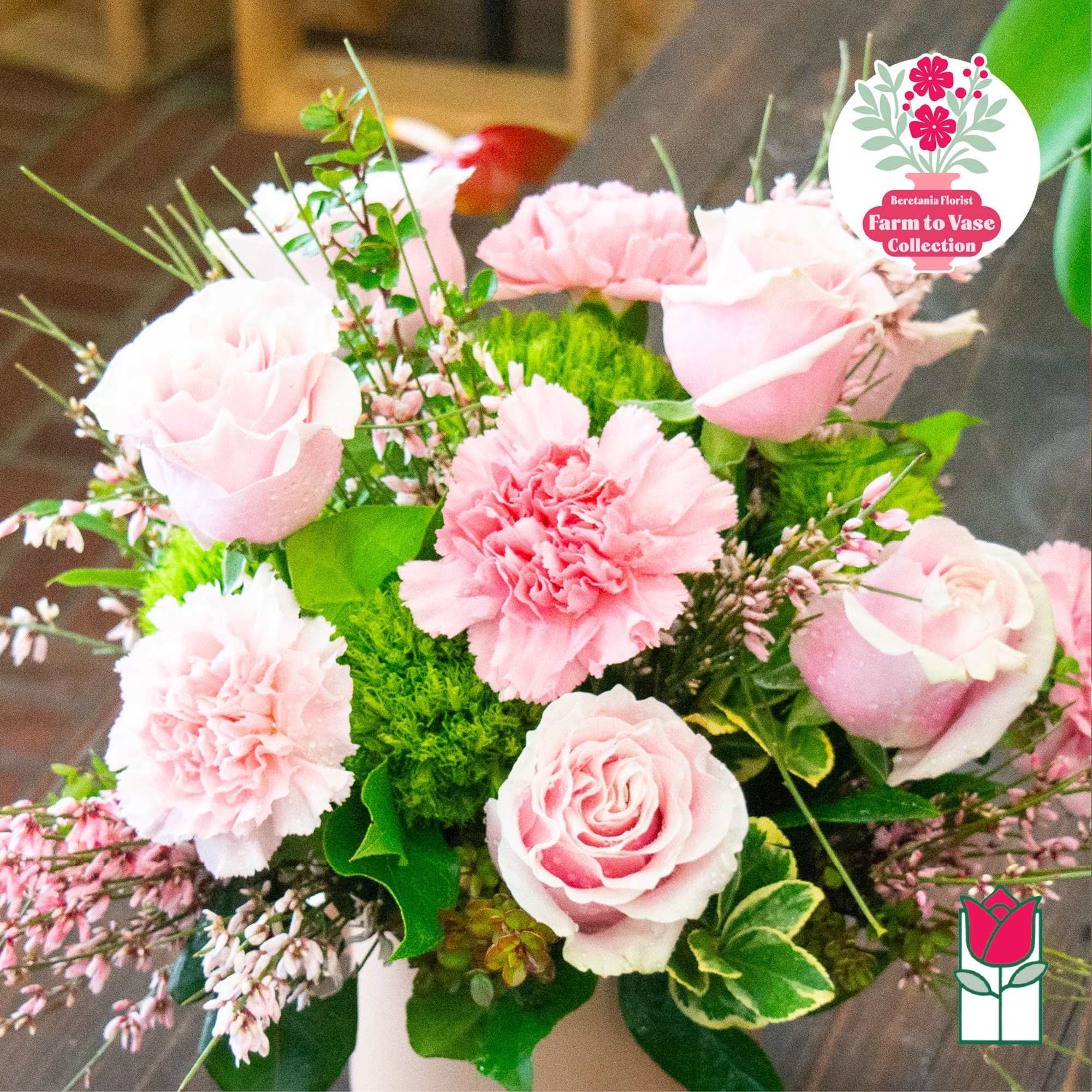 Pink roses and carnations arranged in a vase with green filler