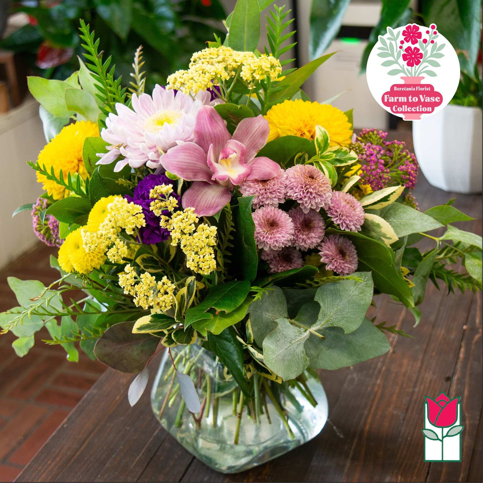 Mixed bouquet of pink, yellow, and purple flowers in a glass vase, photo 2 of 5