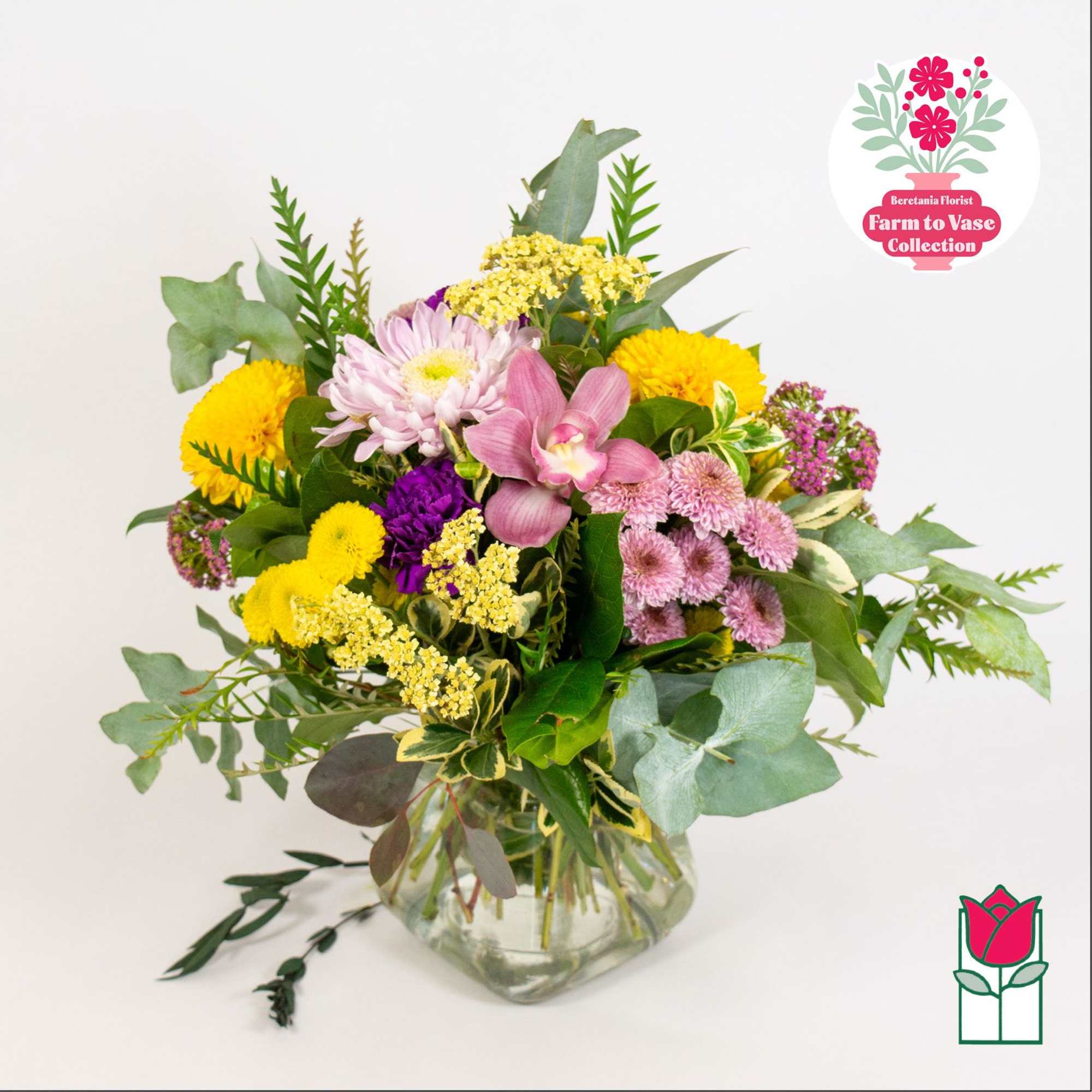 Mixed bouquet of yellow, pink, and purple flowers in a glass vase