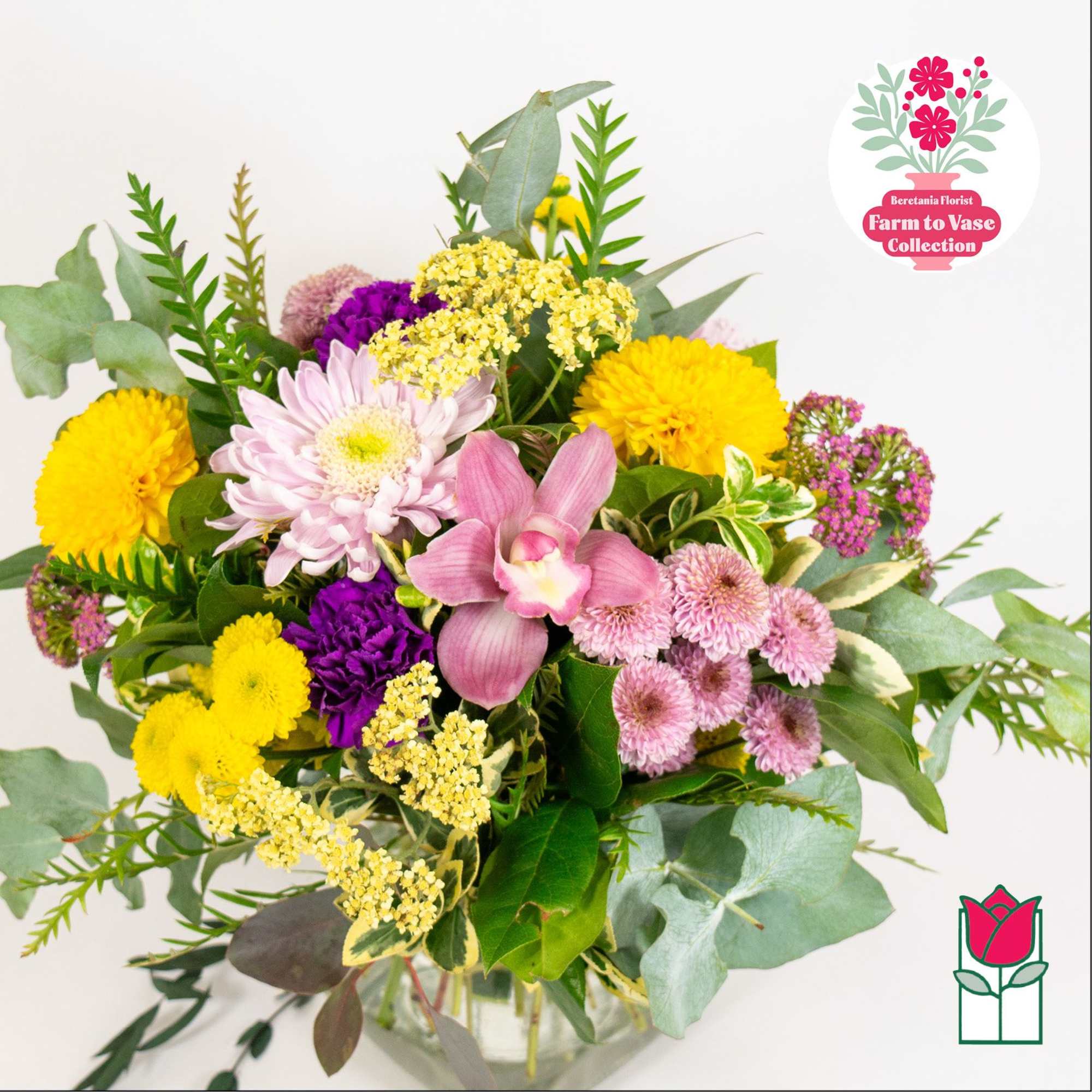 Mixed bouquet with yellow, pink, purple, and white flowers in a glass vase