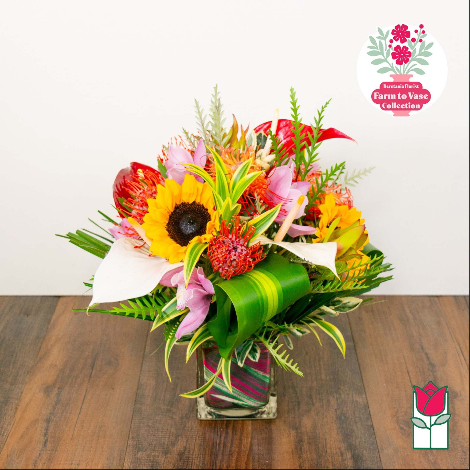 Bright mixed bouquet with sunflowers, lilies, and tropical flowers in a glass vase