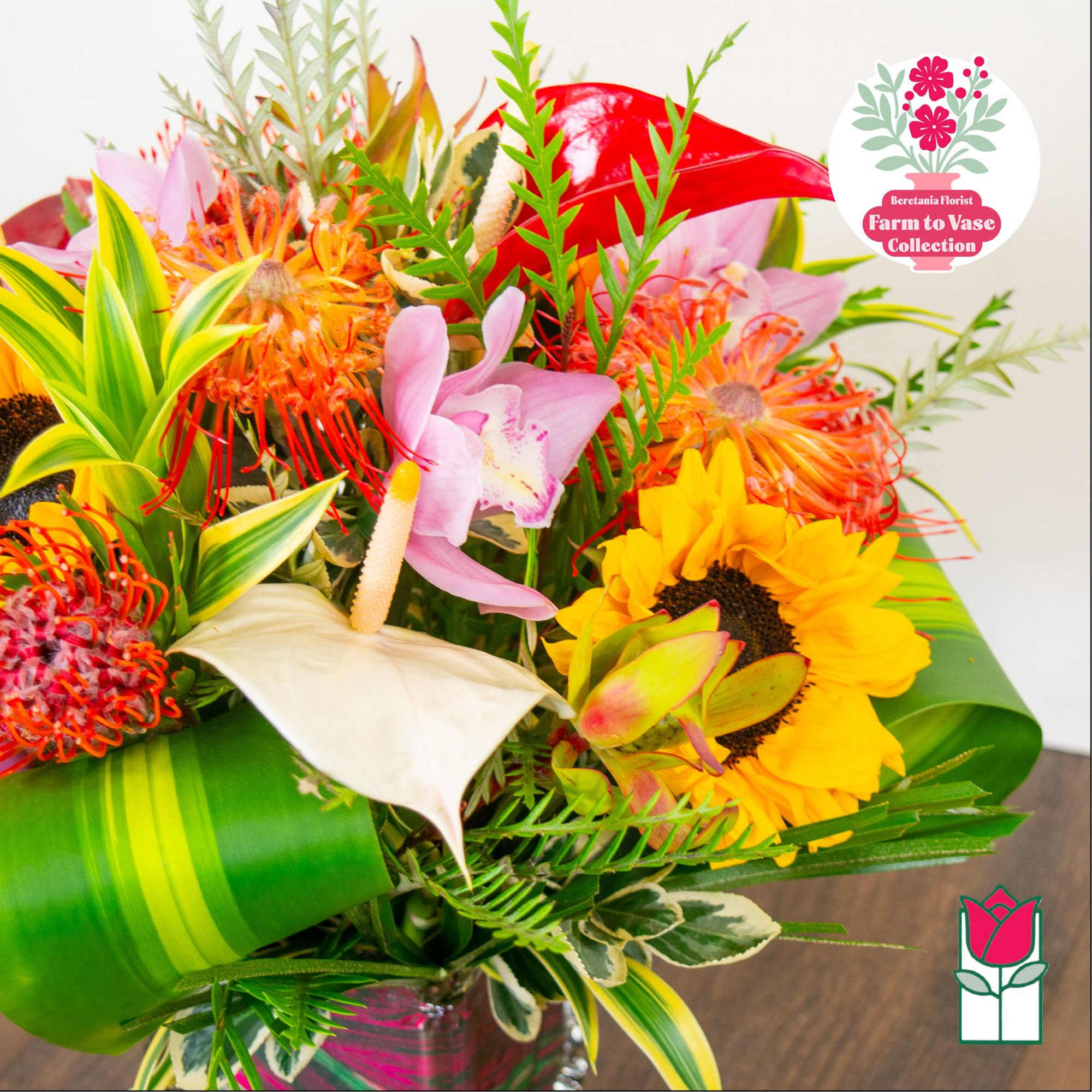 Tropical bouquet with sunflowers, orchids, and anthurium in a glass vase