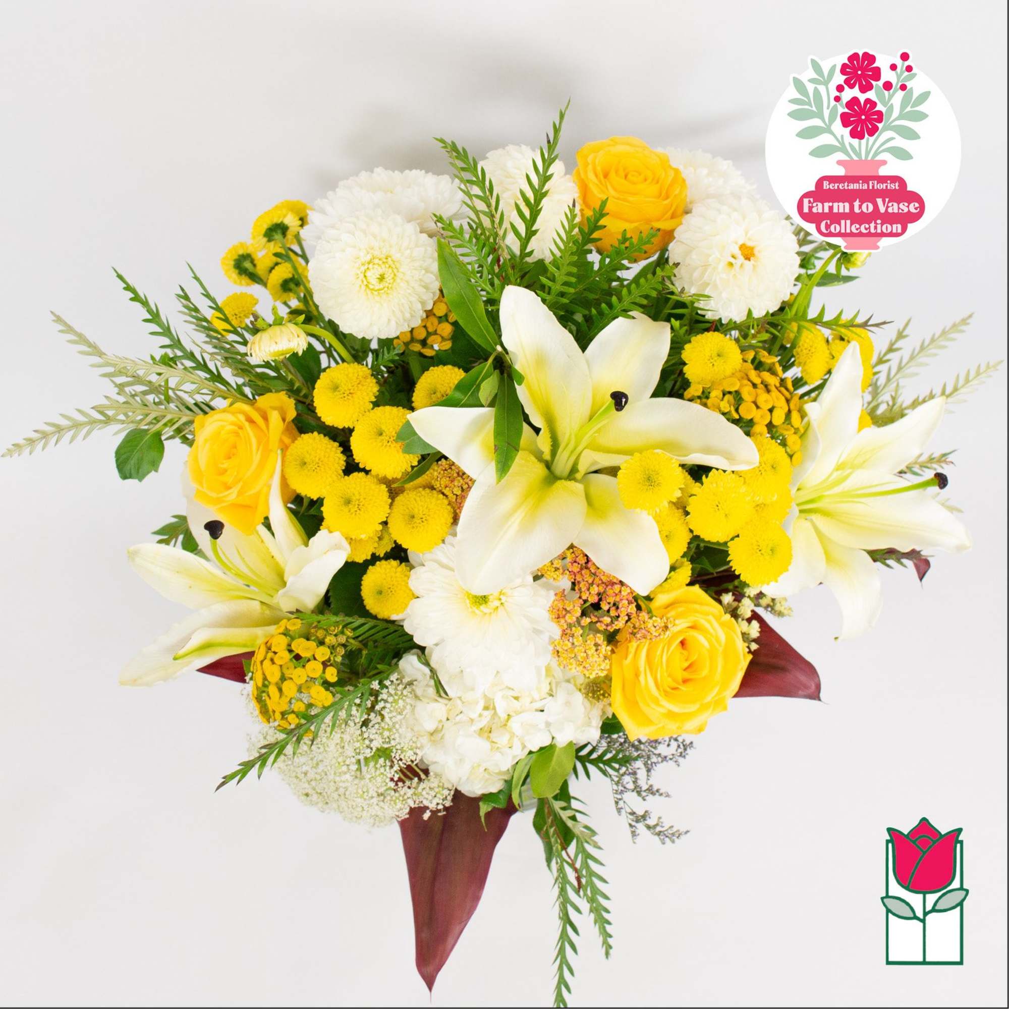 Yellow roses and white lilies arranged with white blooms in a bouquet.