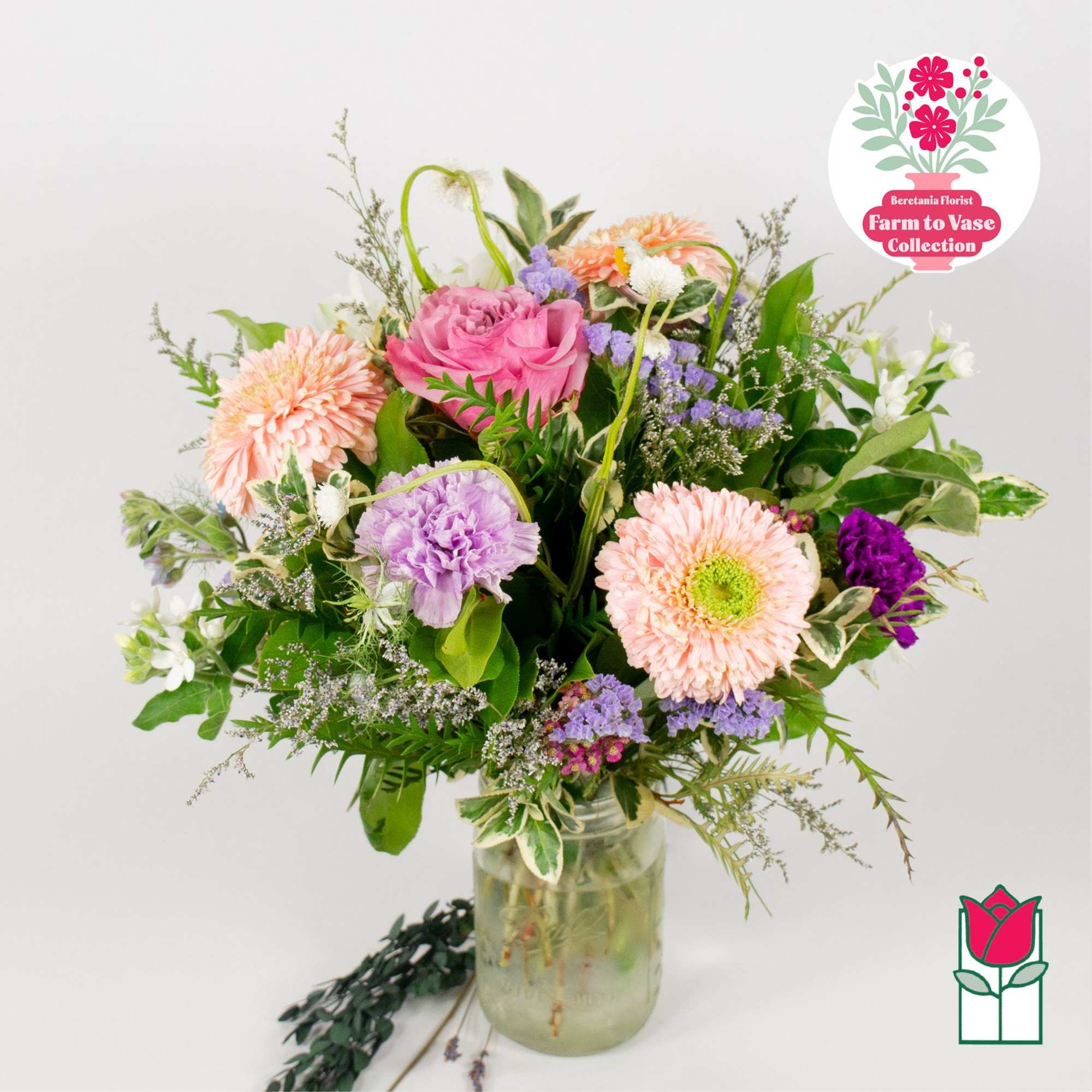 Mixed pink and purple flowers in a glass jar vase