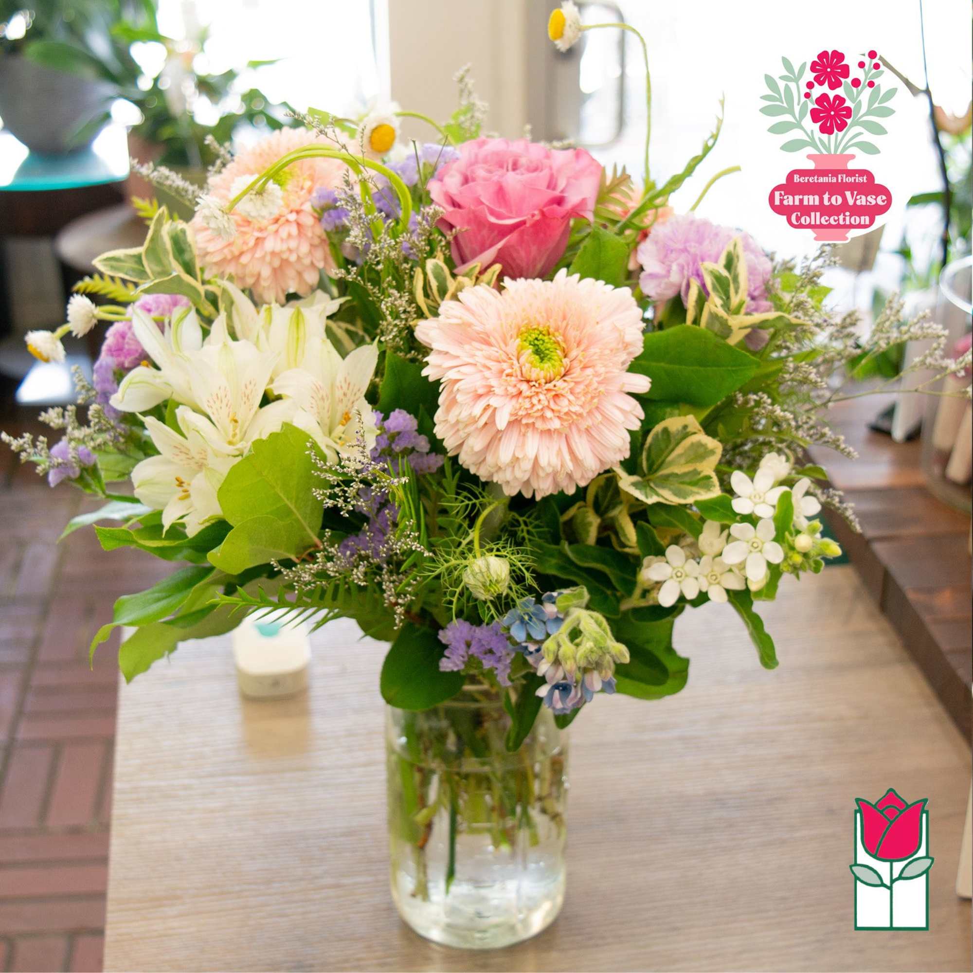 Mixed bouquet of pink, white, and lavender flowers in a glass vase