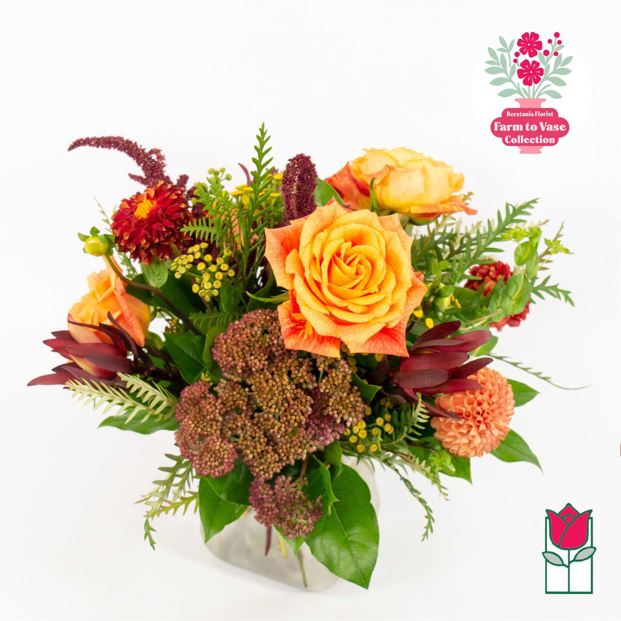 Orange roses and mixed flowers arranged in a clear vase