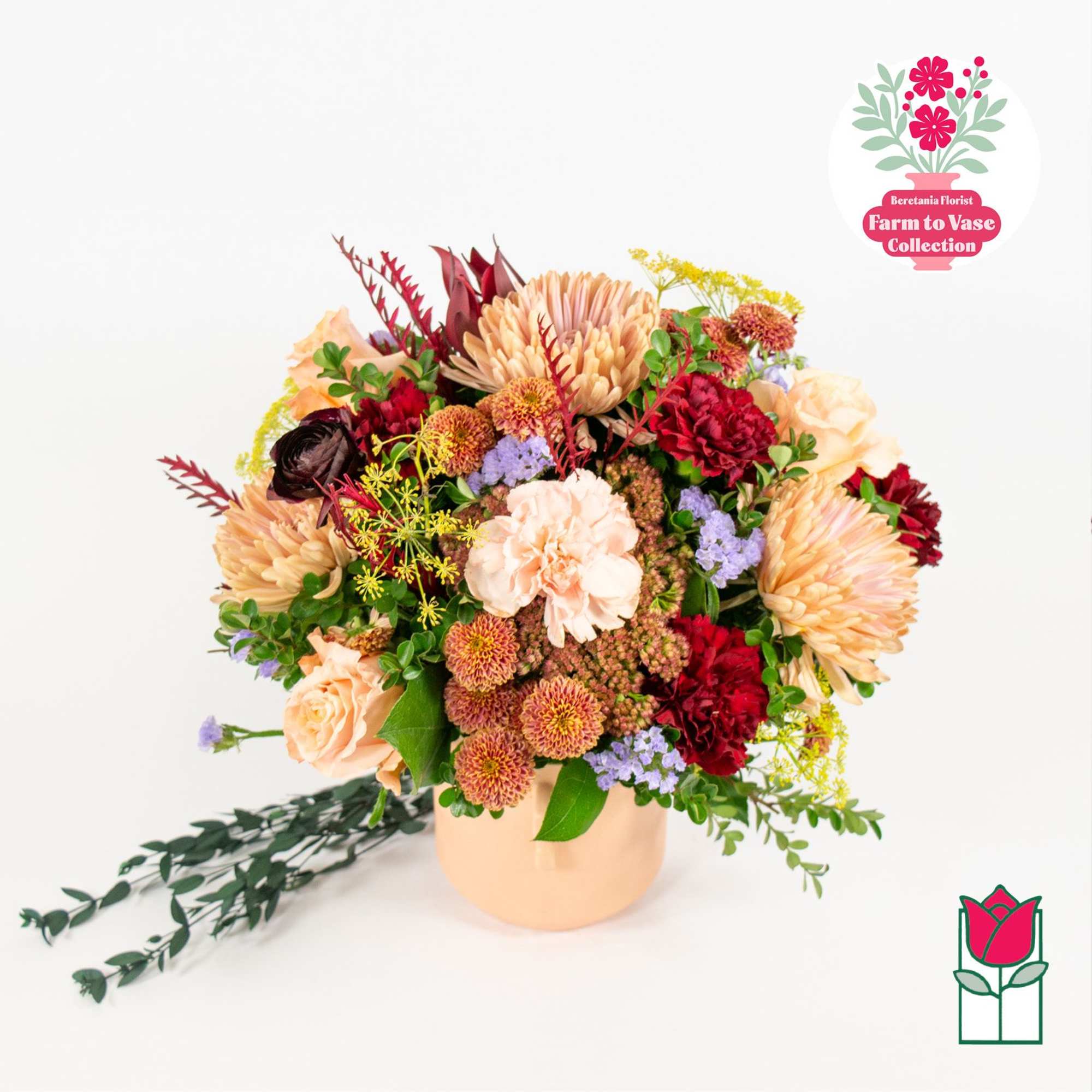 Mixed bouquet in a peach vase with peach, red, and lavender flowers